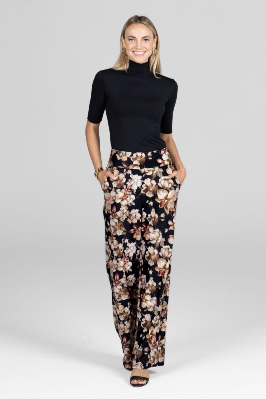 Woman wearing a black turtleneck and floral pants on a white background