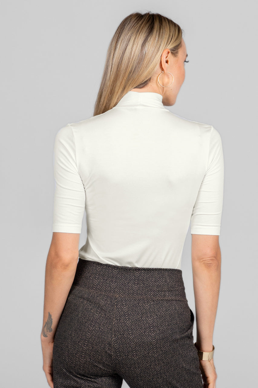 Person wearing a white short-sleeve shirt and dark pants on a gray background