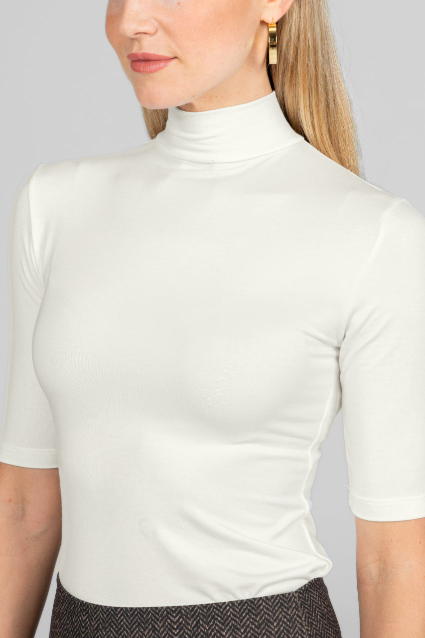 White turtleneck top worn by a person on a plain background