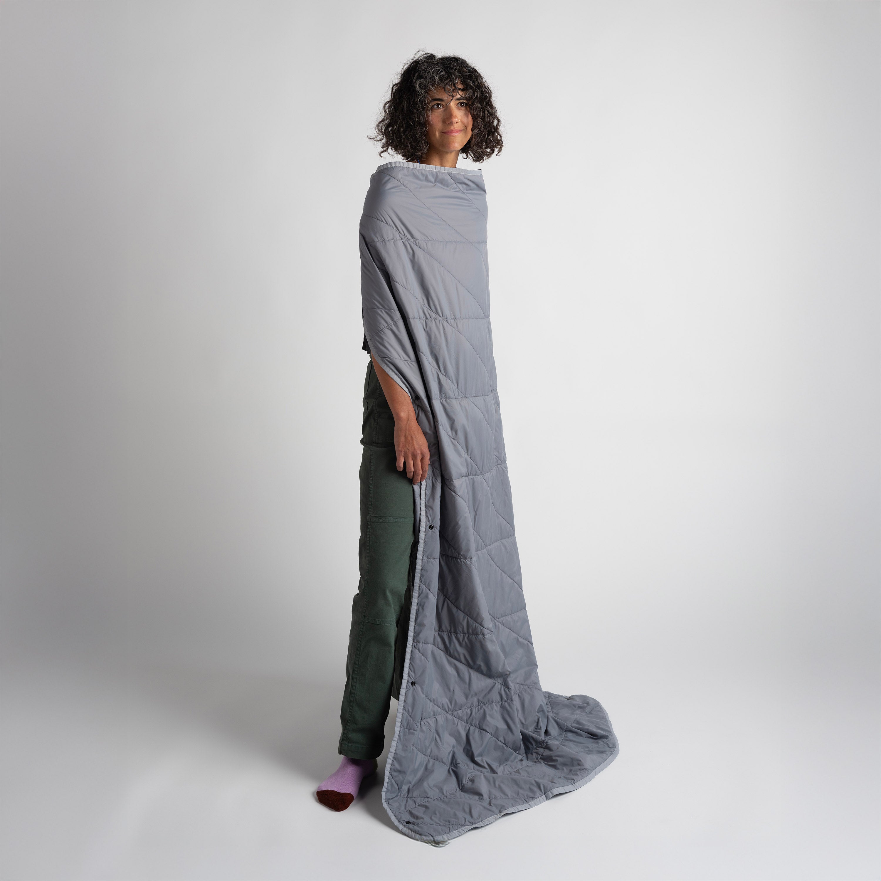Person wearing a long, light gray quilted cover over their body on a white background