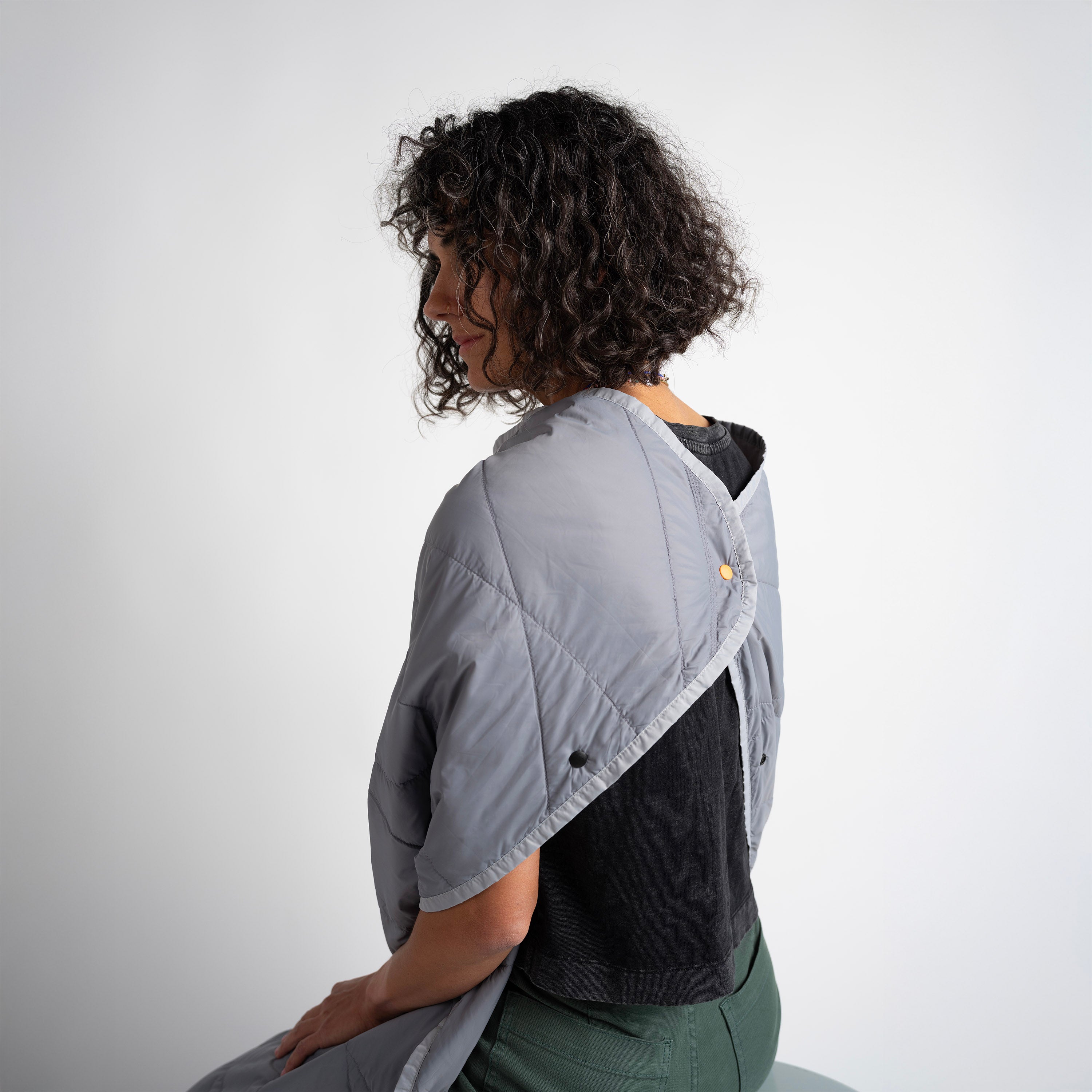 Person wearing a gray quilted jacket over a black shirt on a white background