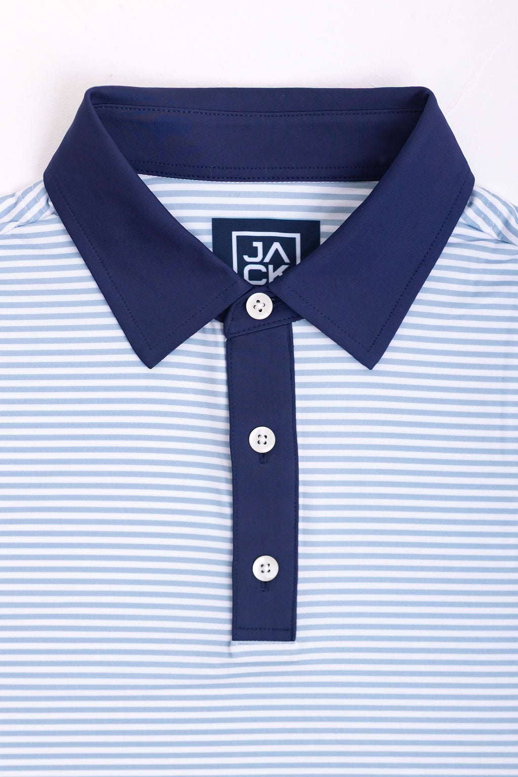 Close-up of a blue and white striped polo shirt with a collar and buttons on a white background.