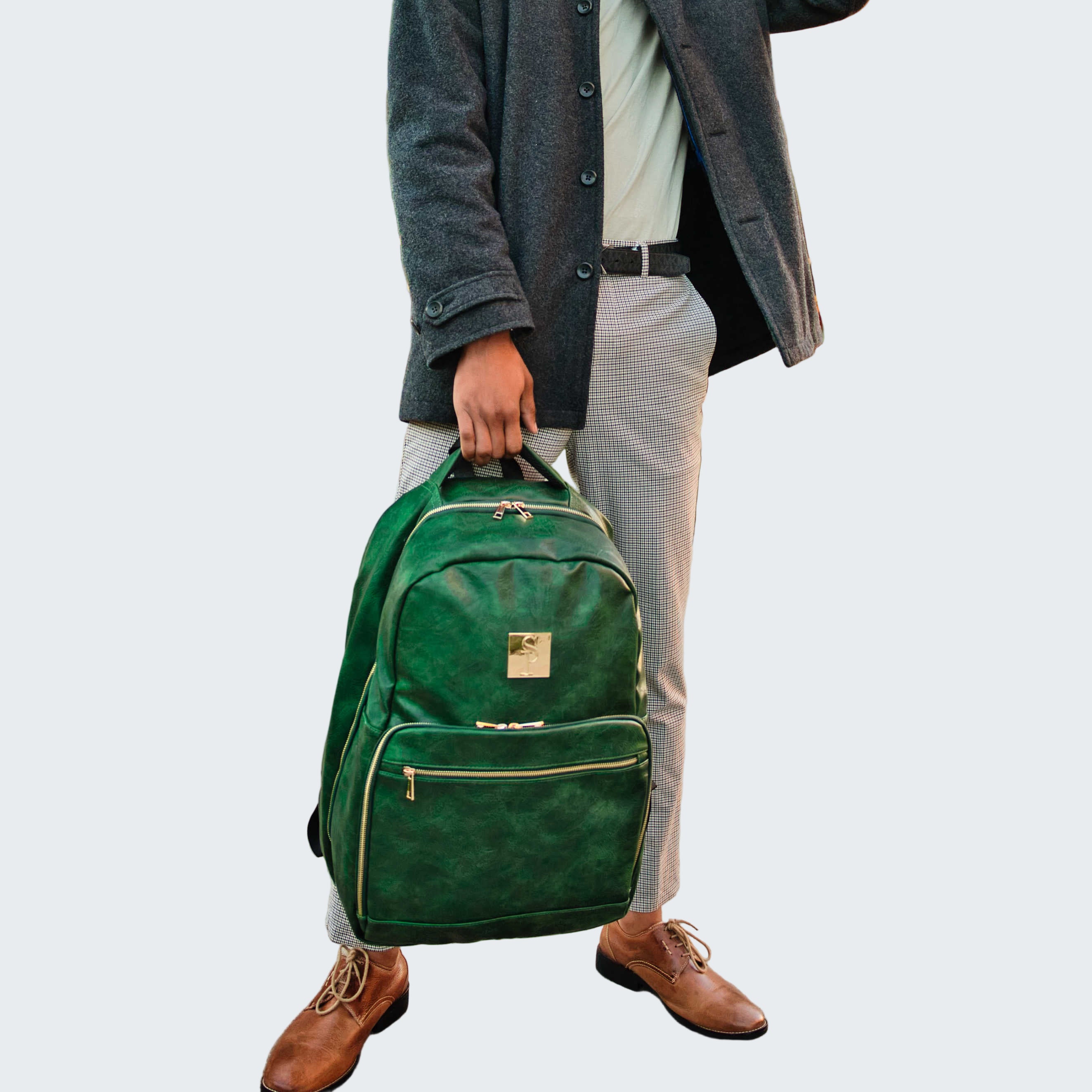 Person holding a green backpack on a sidewalk