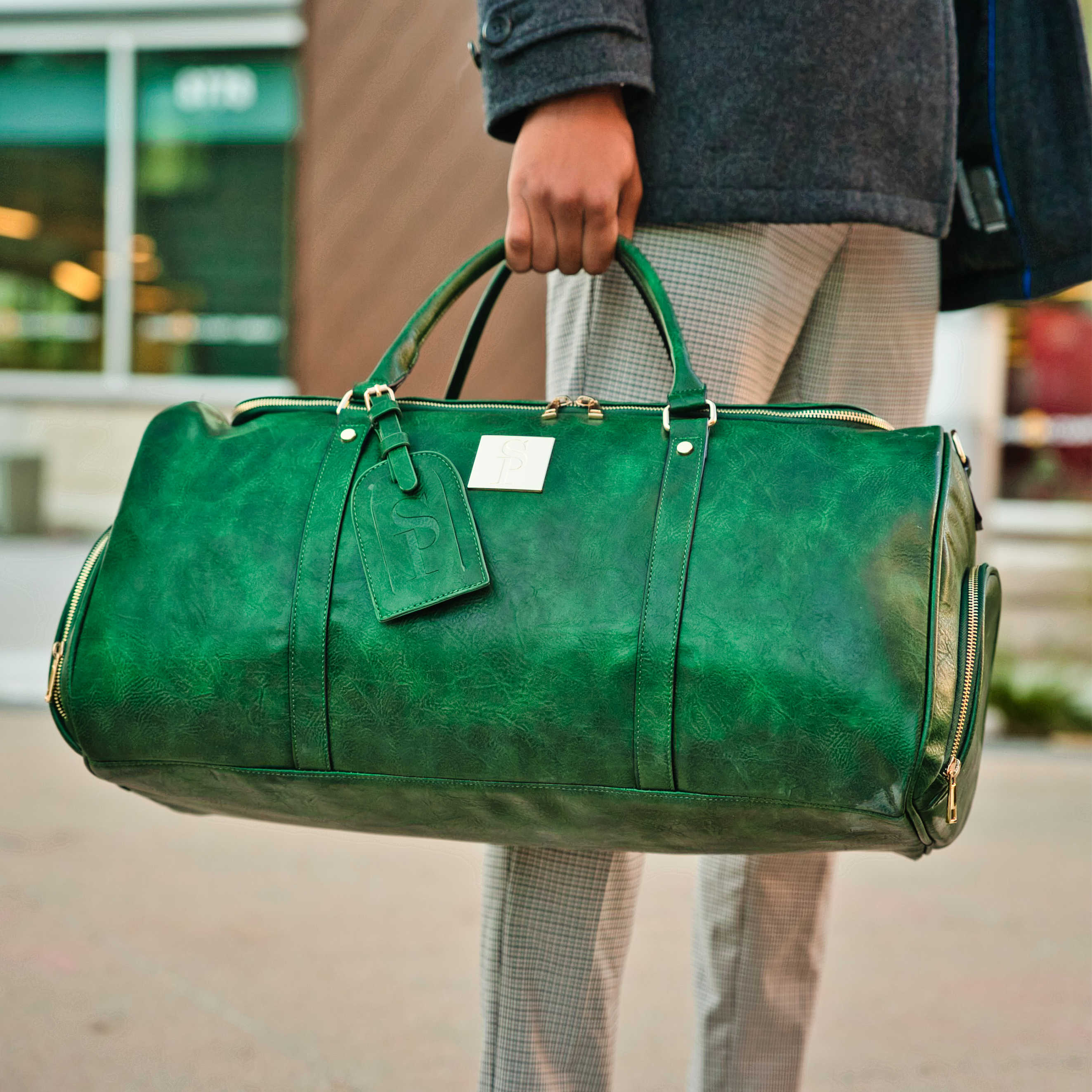 Person holding a green leather duffel bag outdoors