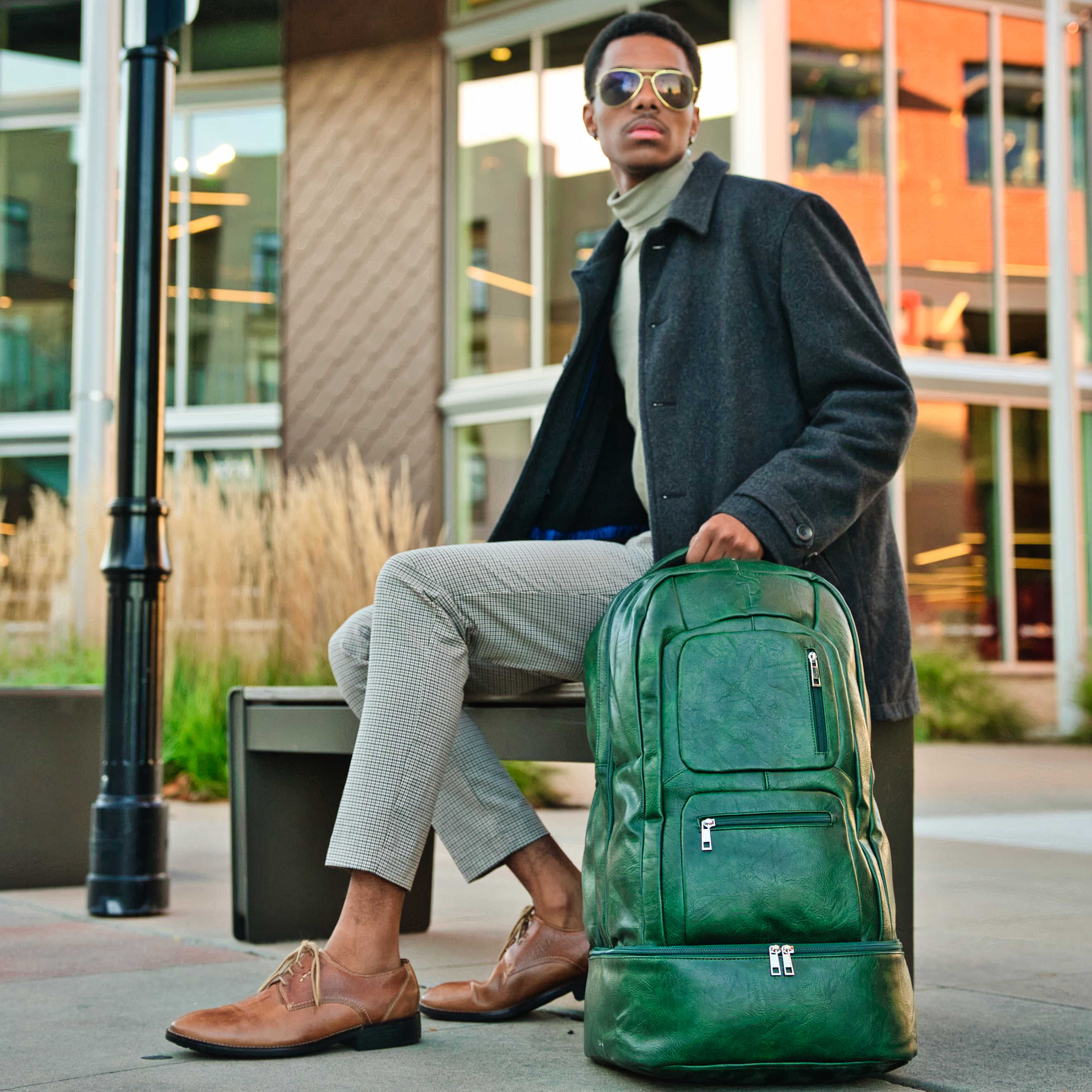 Man sitting with a green backpack in an urban setting