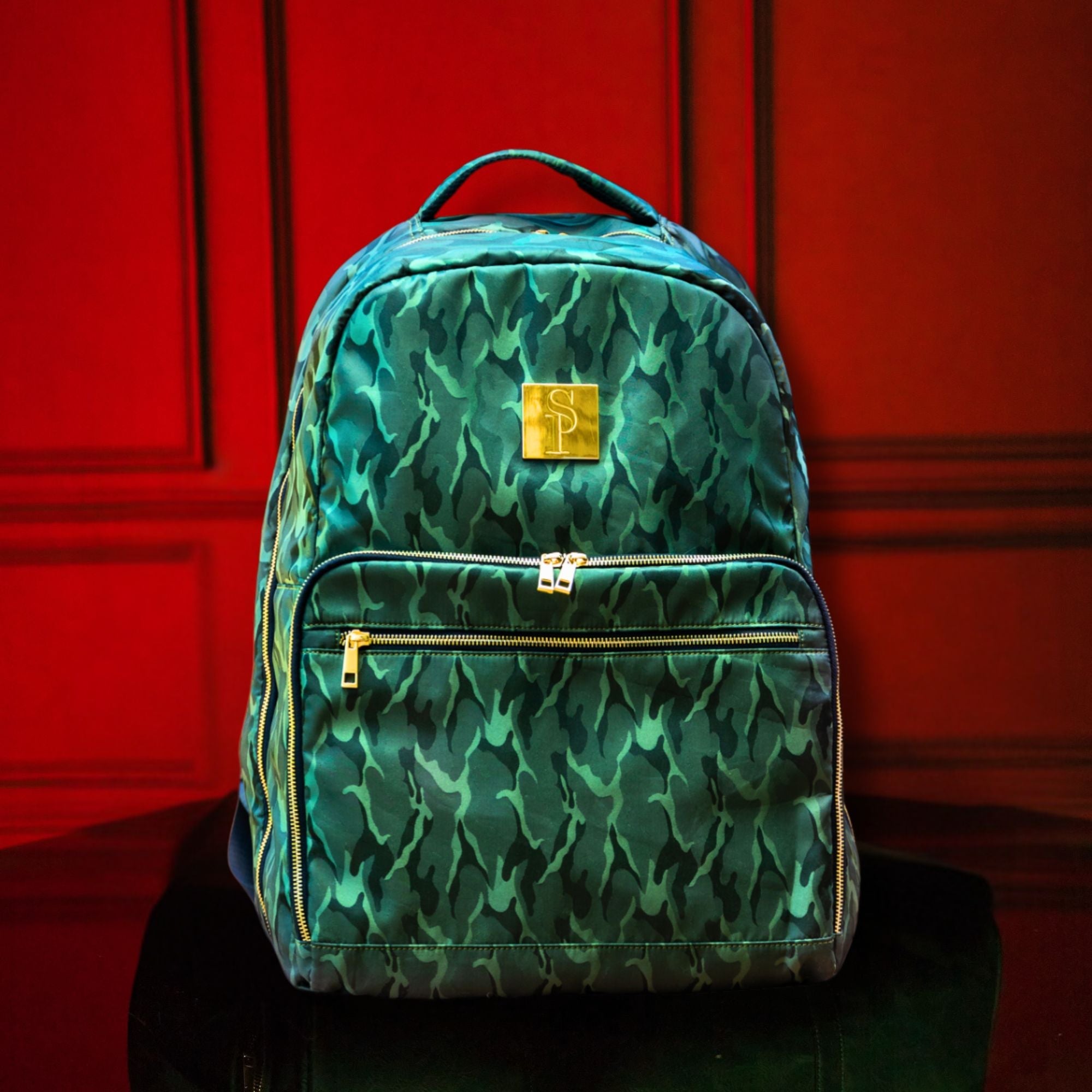 Green patterned backpack with gold accents on a red background