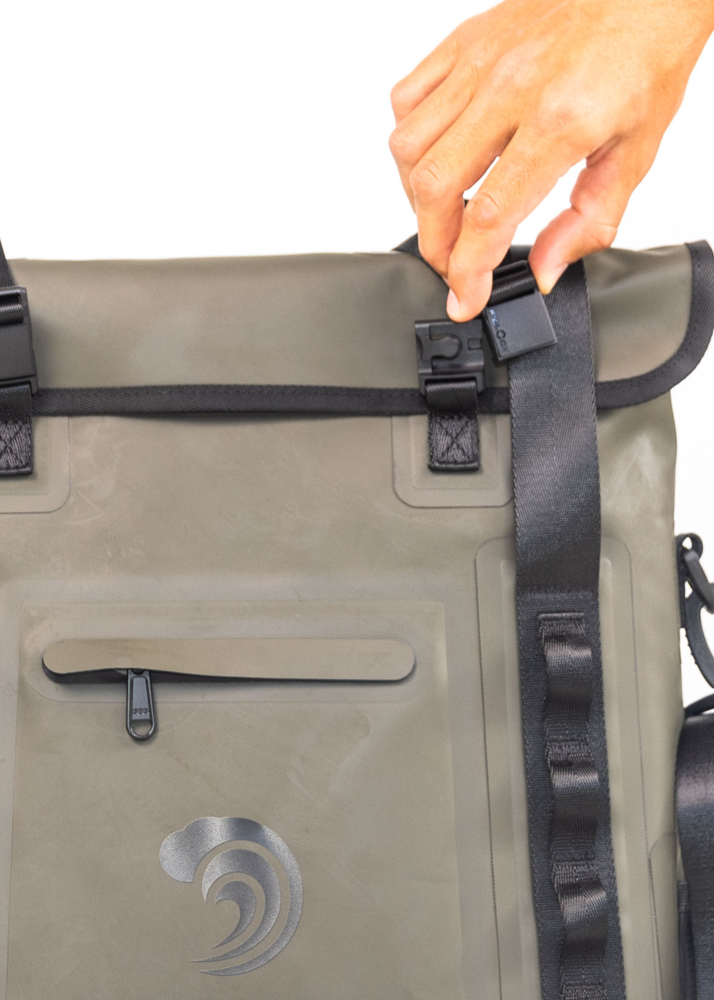 Person securing a strap on a green waterproof bag with a visible brand logo.