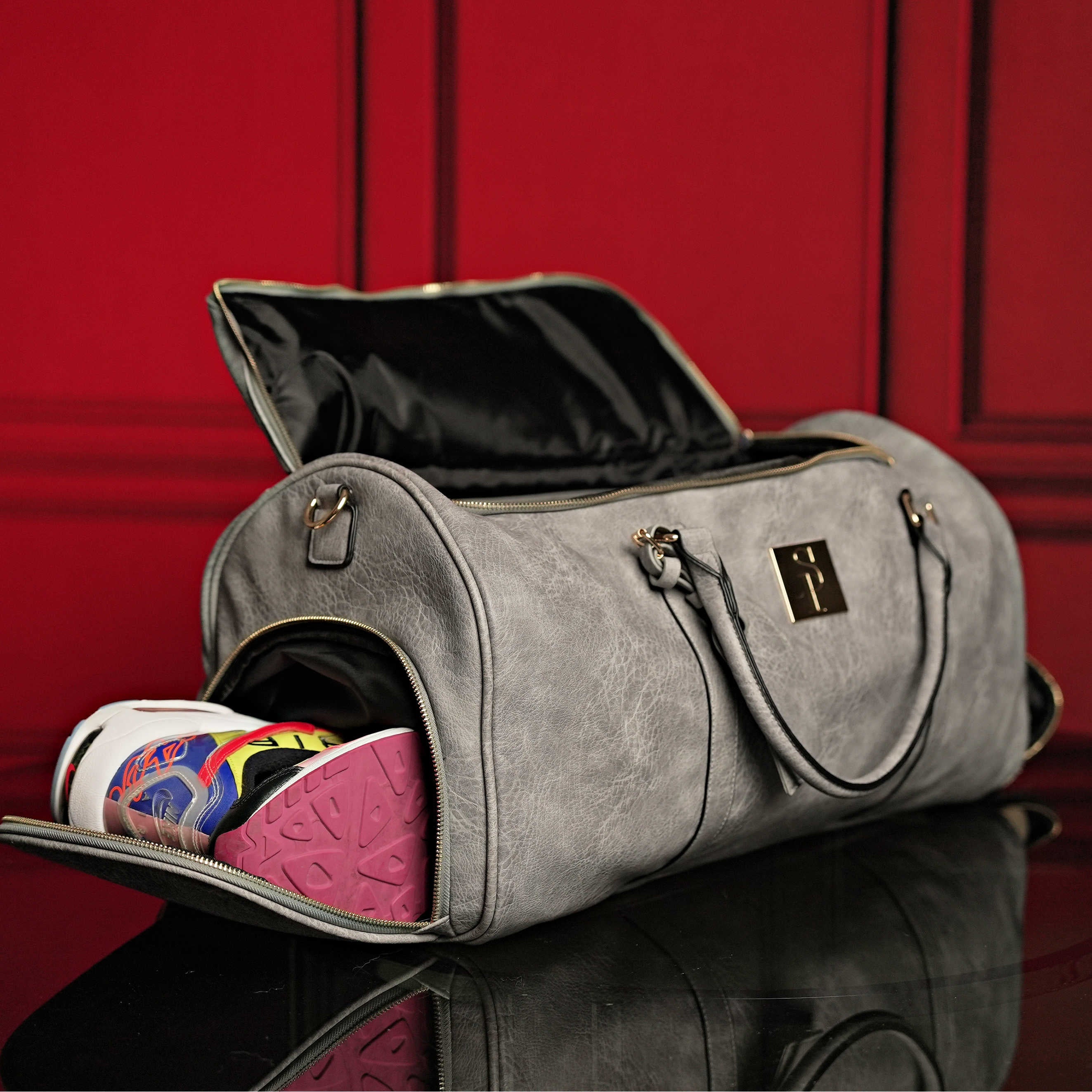 Gray duffel bag with a shoe inside on a red background