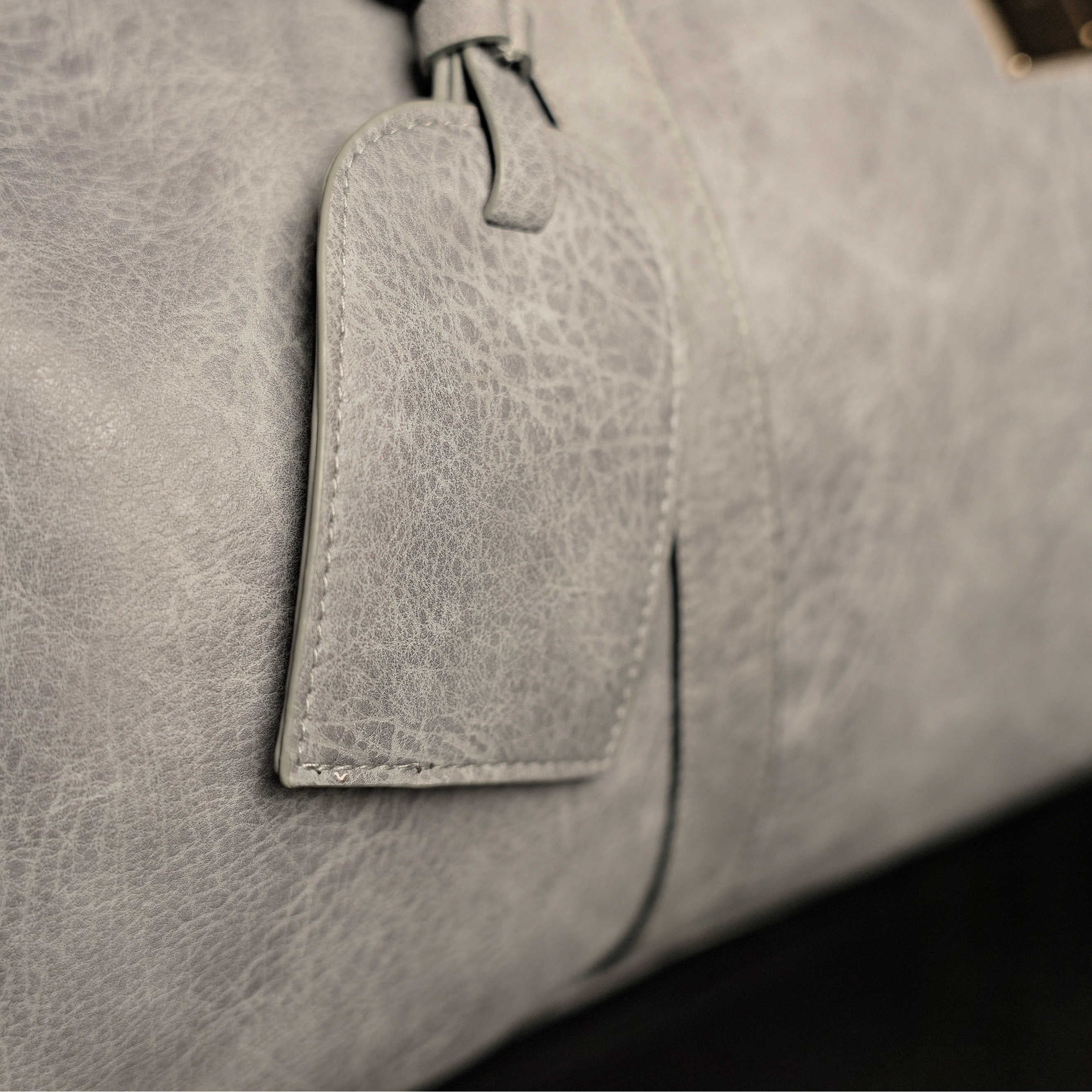 Close-up of a gray leather bag with a tag.