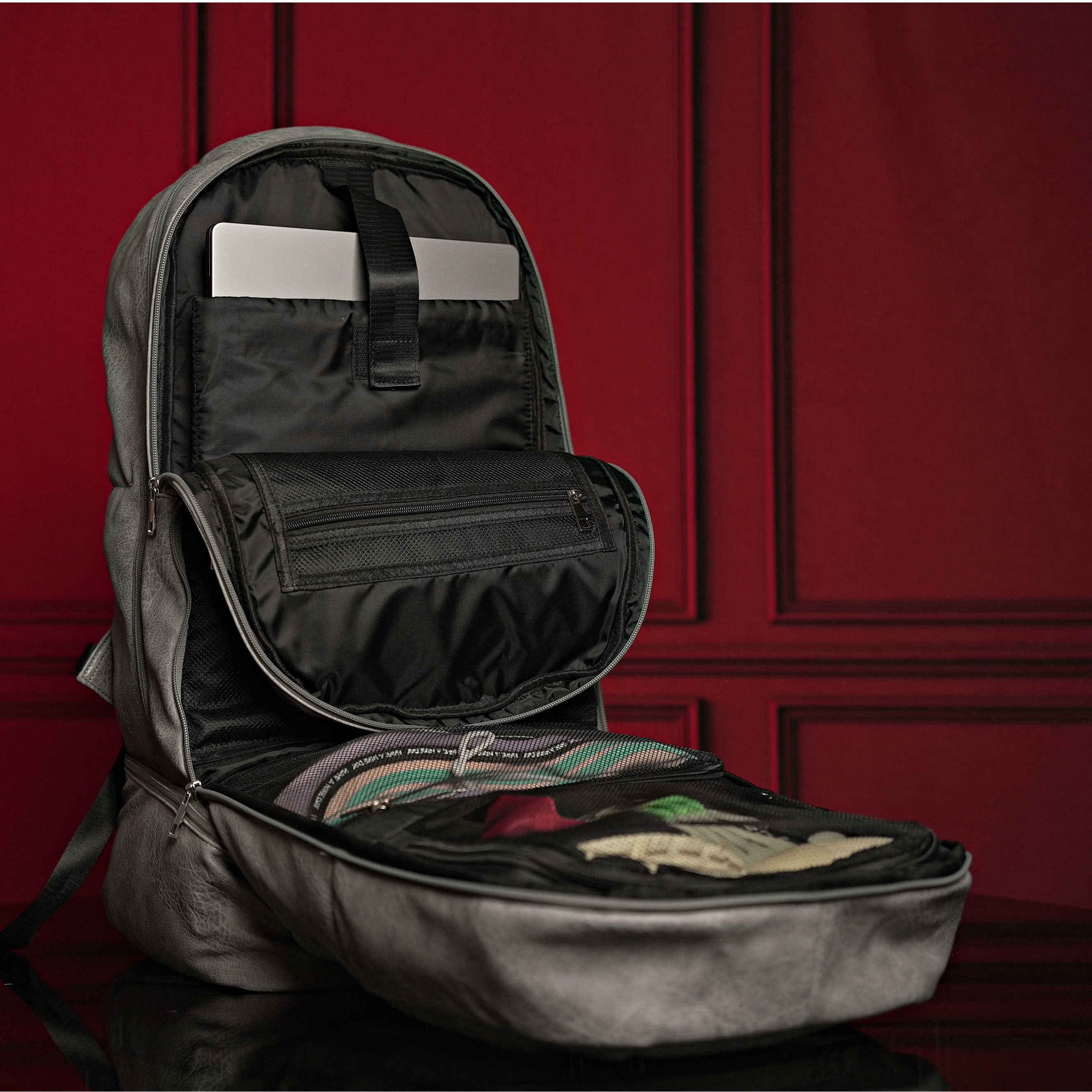Open black backpack with items inside against a red paneled wall