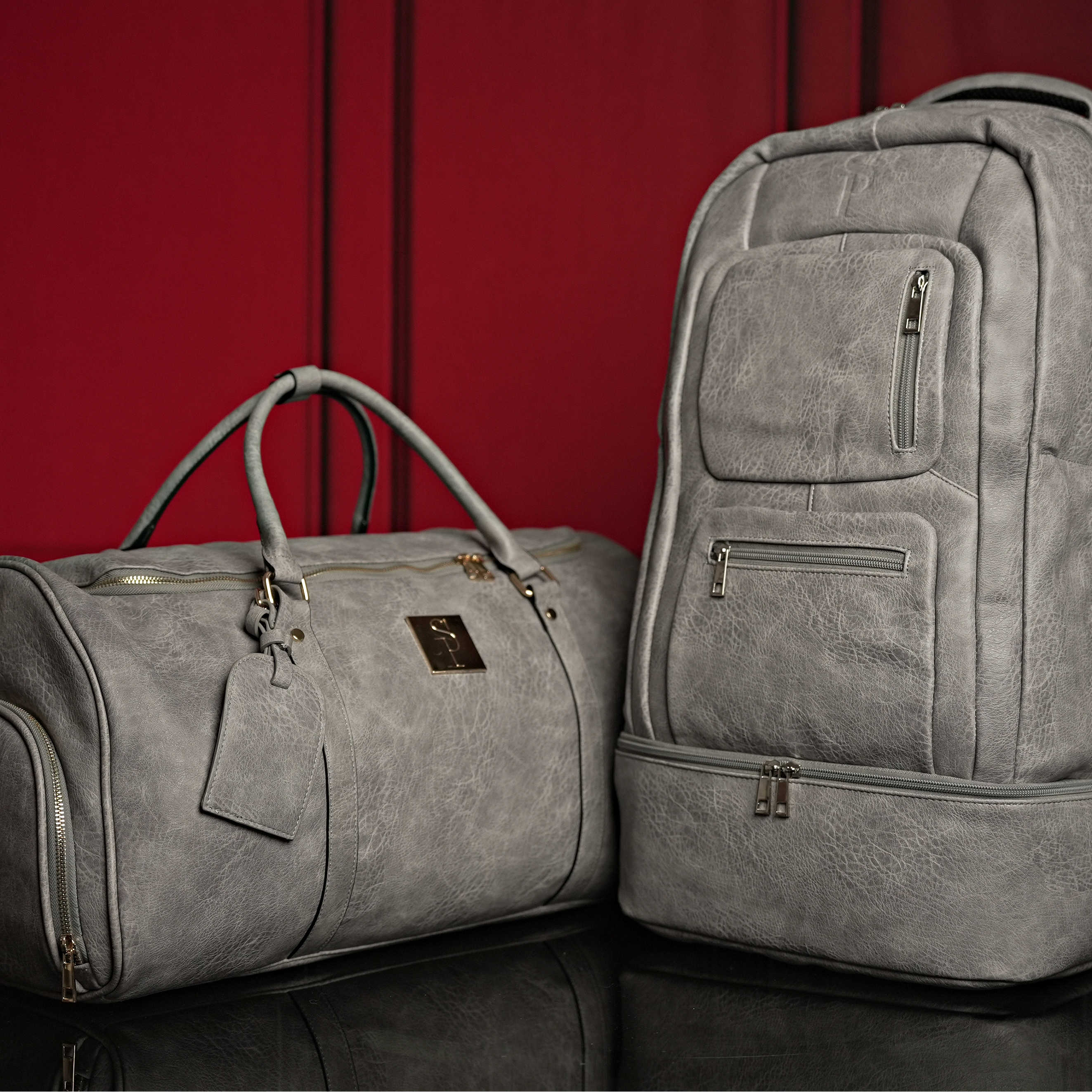 Gray duffel bag and backpack on a red background