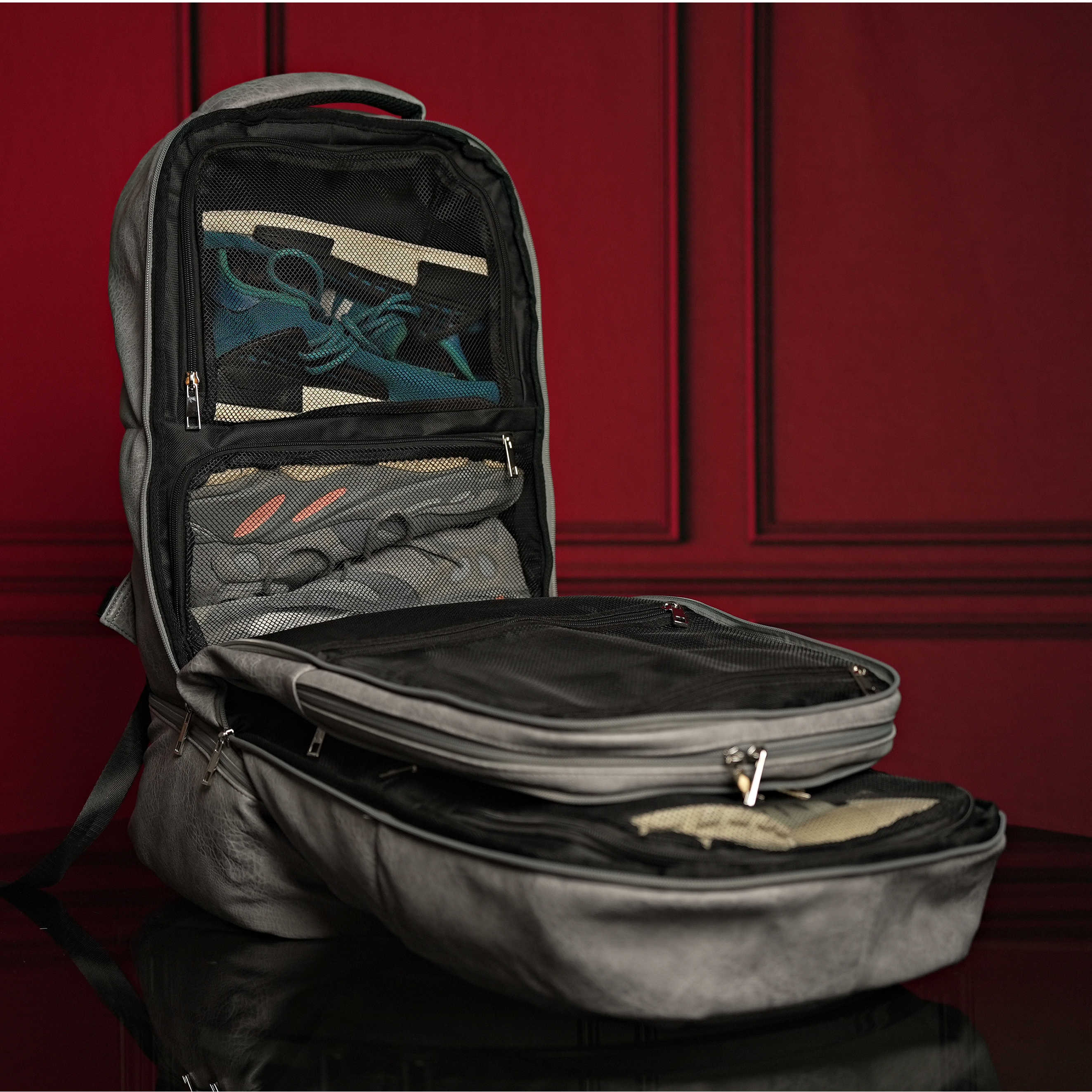 Open black backpack with compartments on a red background