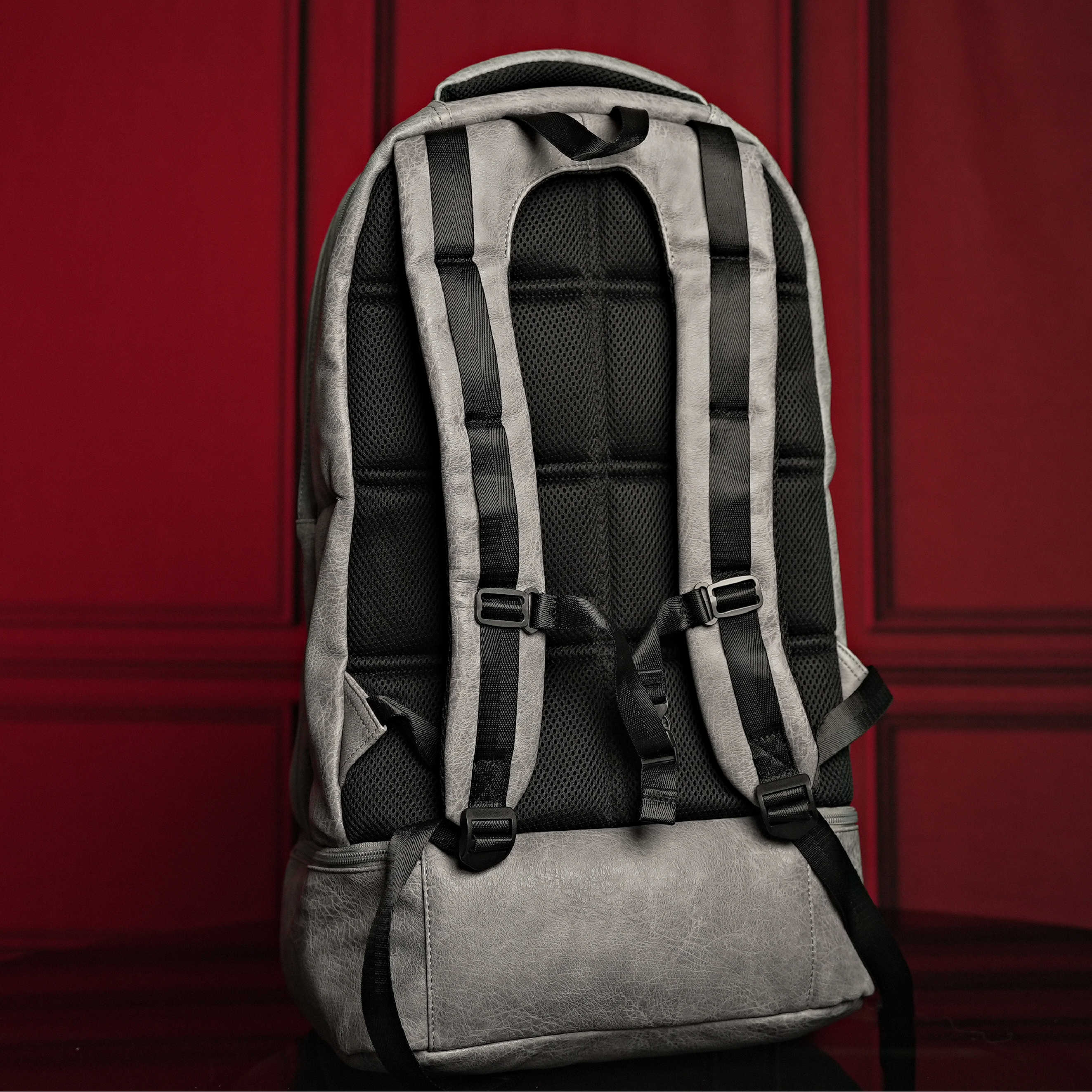 Gray backpack with black straps on a red background