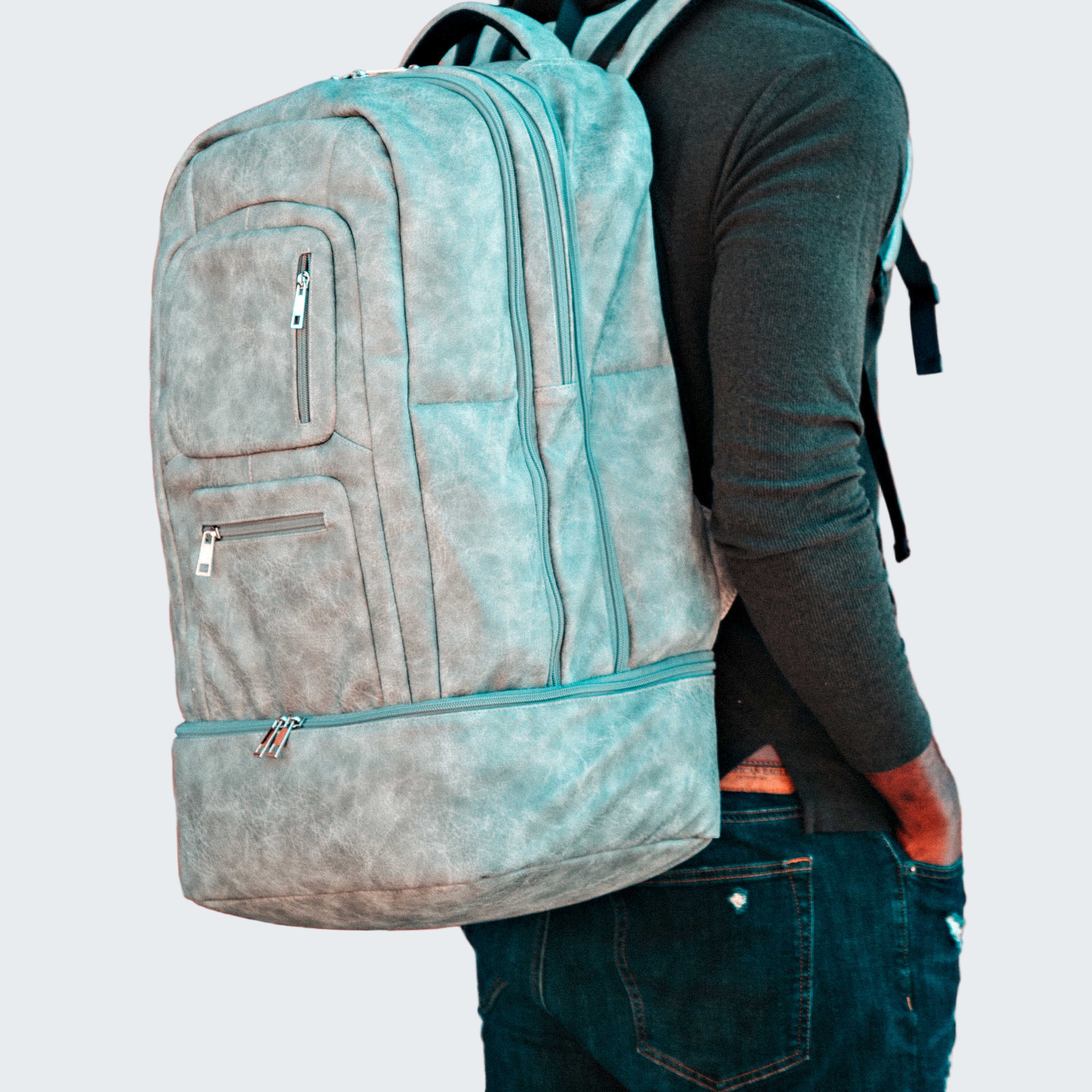 Person wearing a light blue backpack against a brick wall