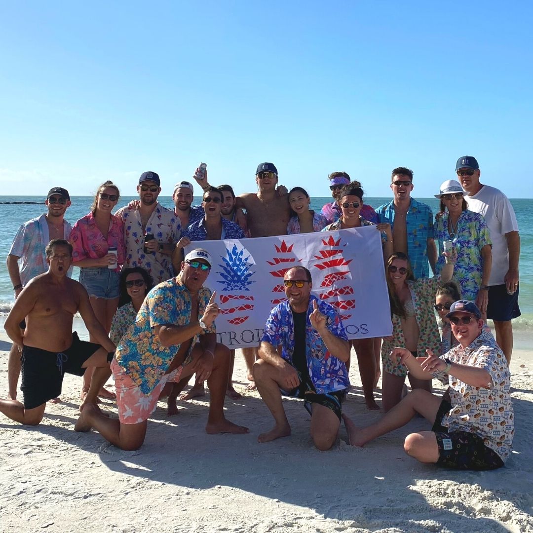 Group of people on a beach holding a colorful banner
