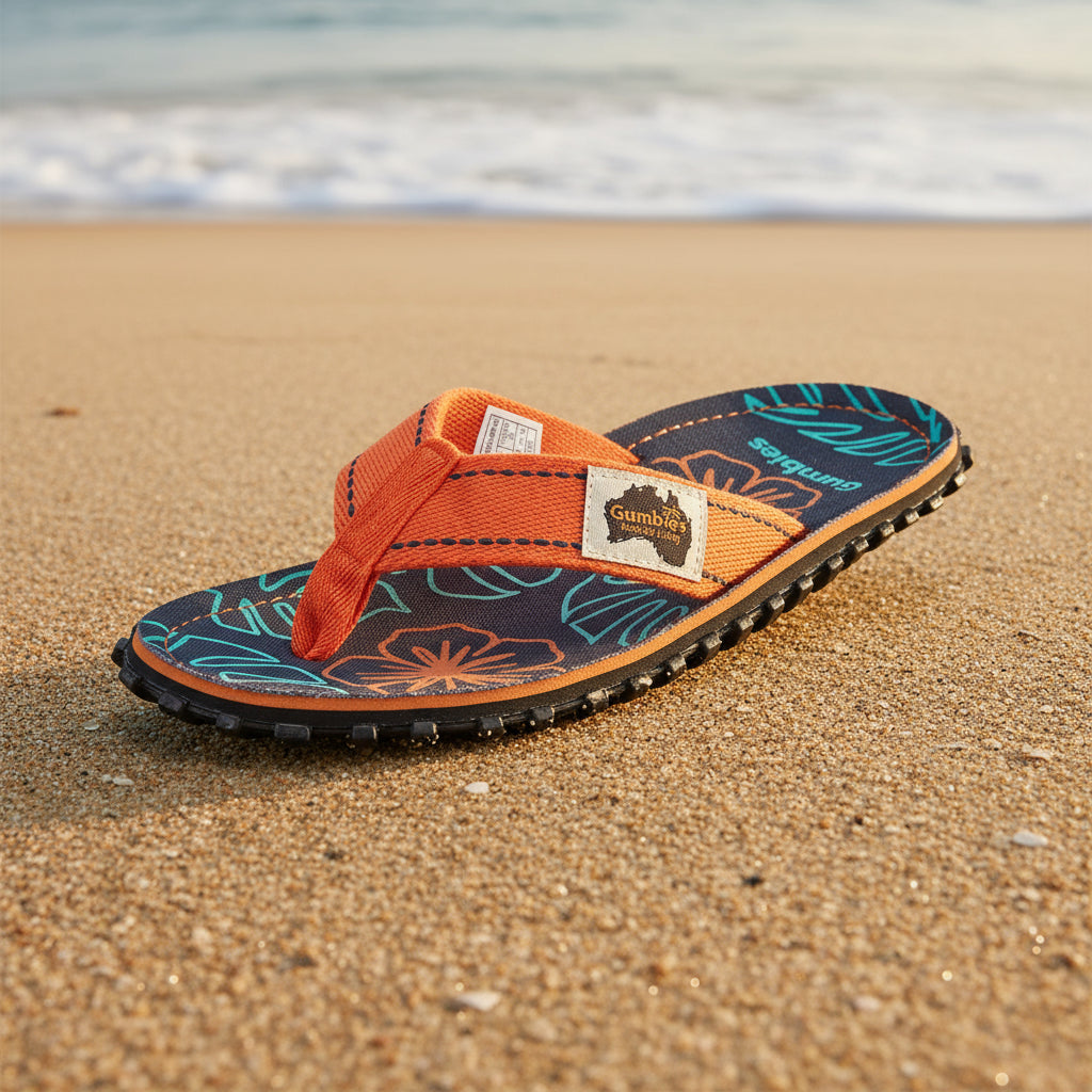 Flip-flop sandal with orange strap and floral pattern on a white background