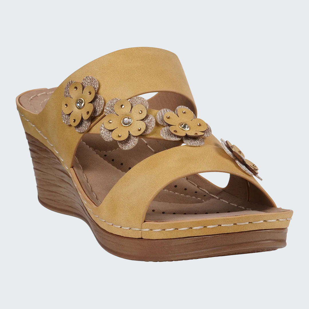 Beige wedge sandal with floral decorations on a white background