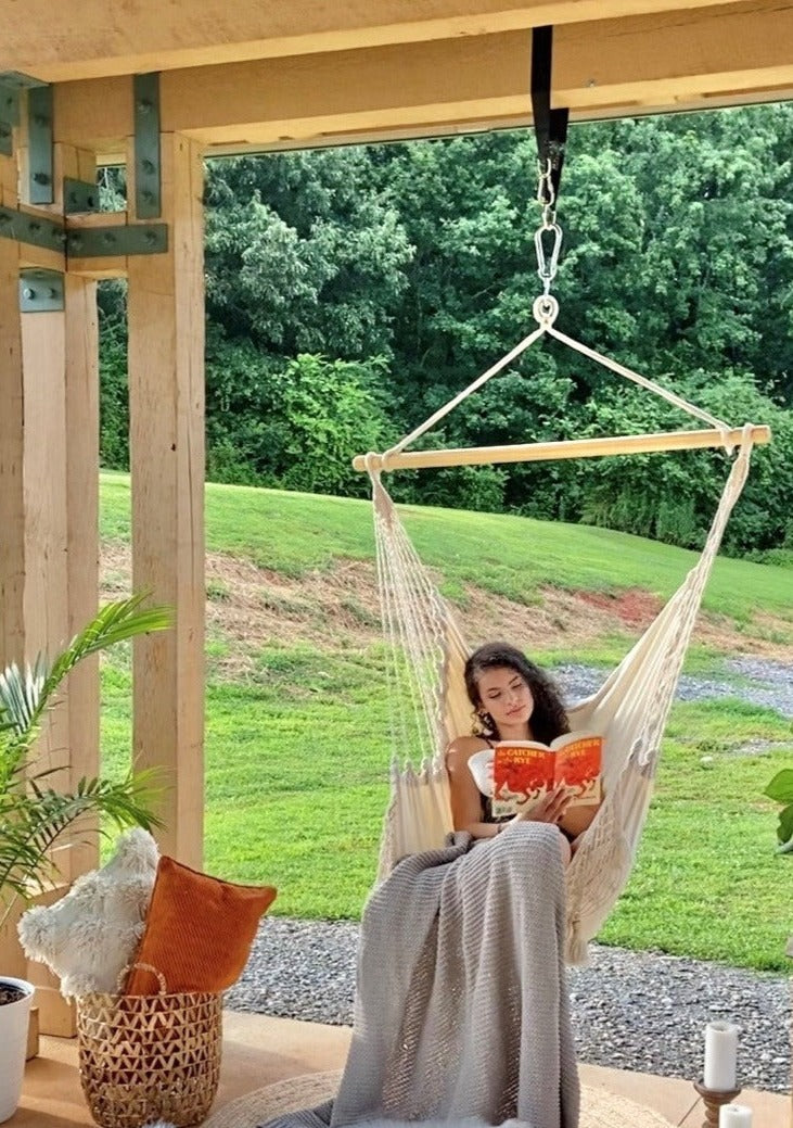 Woman reading a book in a hammock on a wooden deck with a scenic background