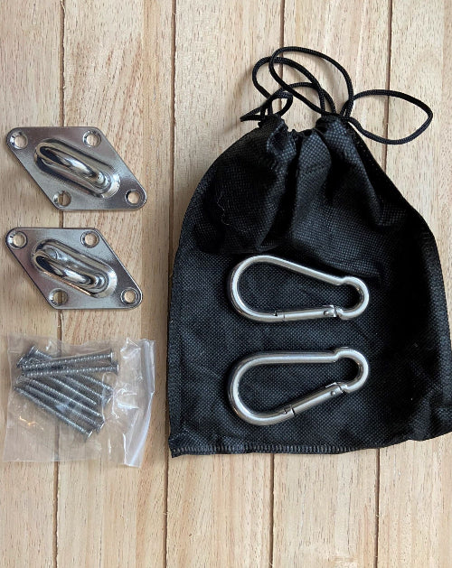Metal carabiners, screws, and a black drawstring bag on a wooden surface