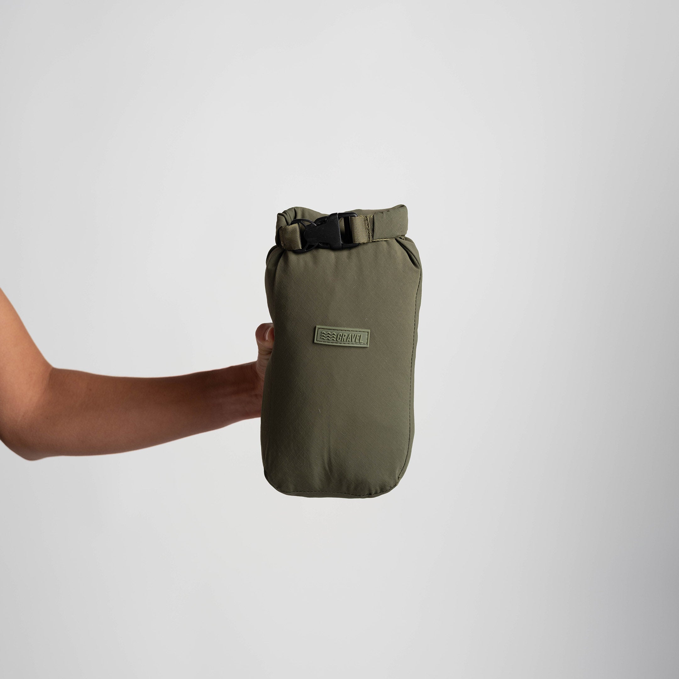 Green waterproof bag held by a person on a white background