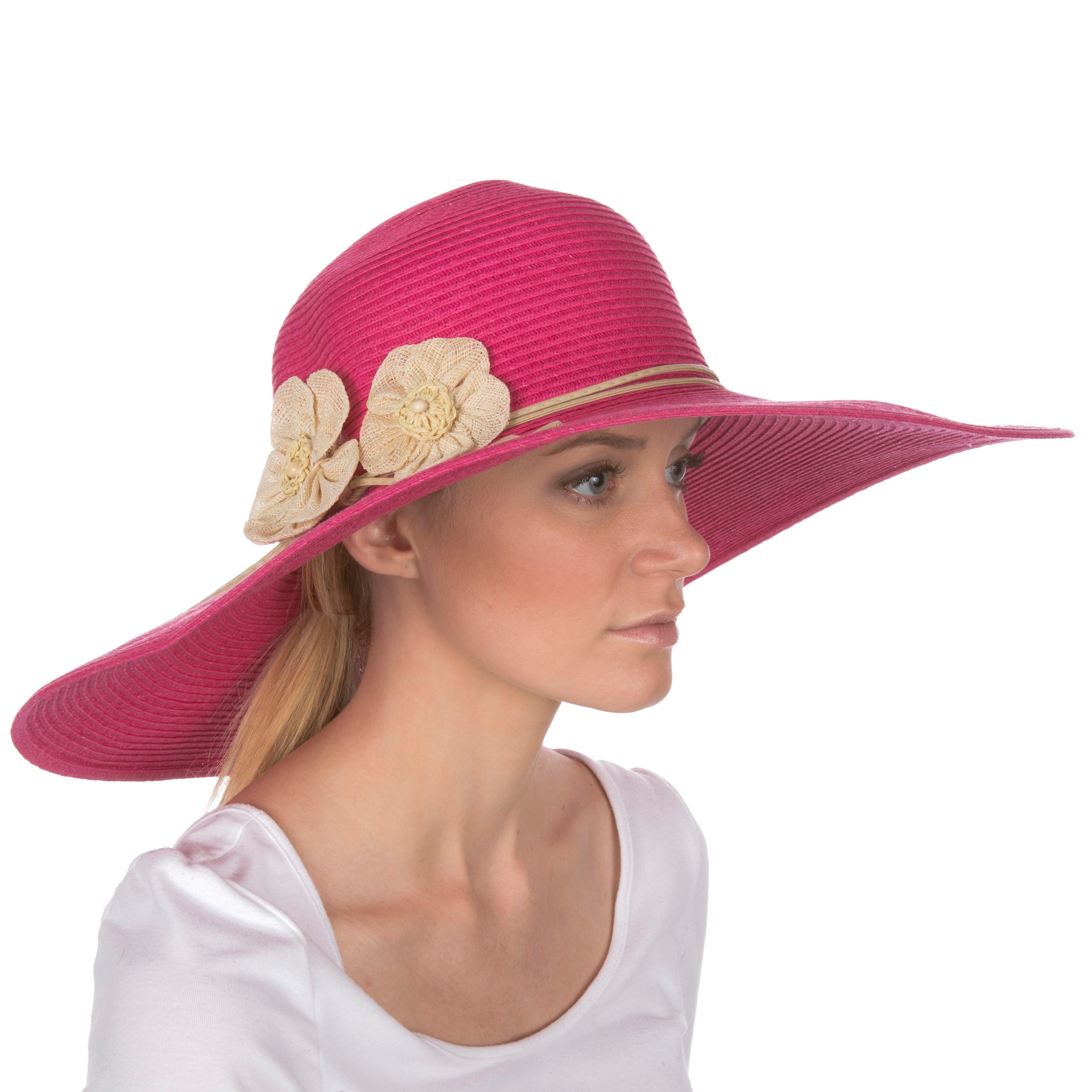 Woman wearing a pink sun hat with floral decorations on a white background