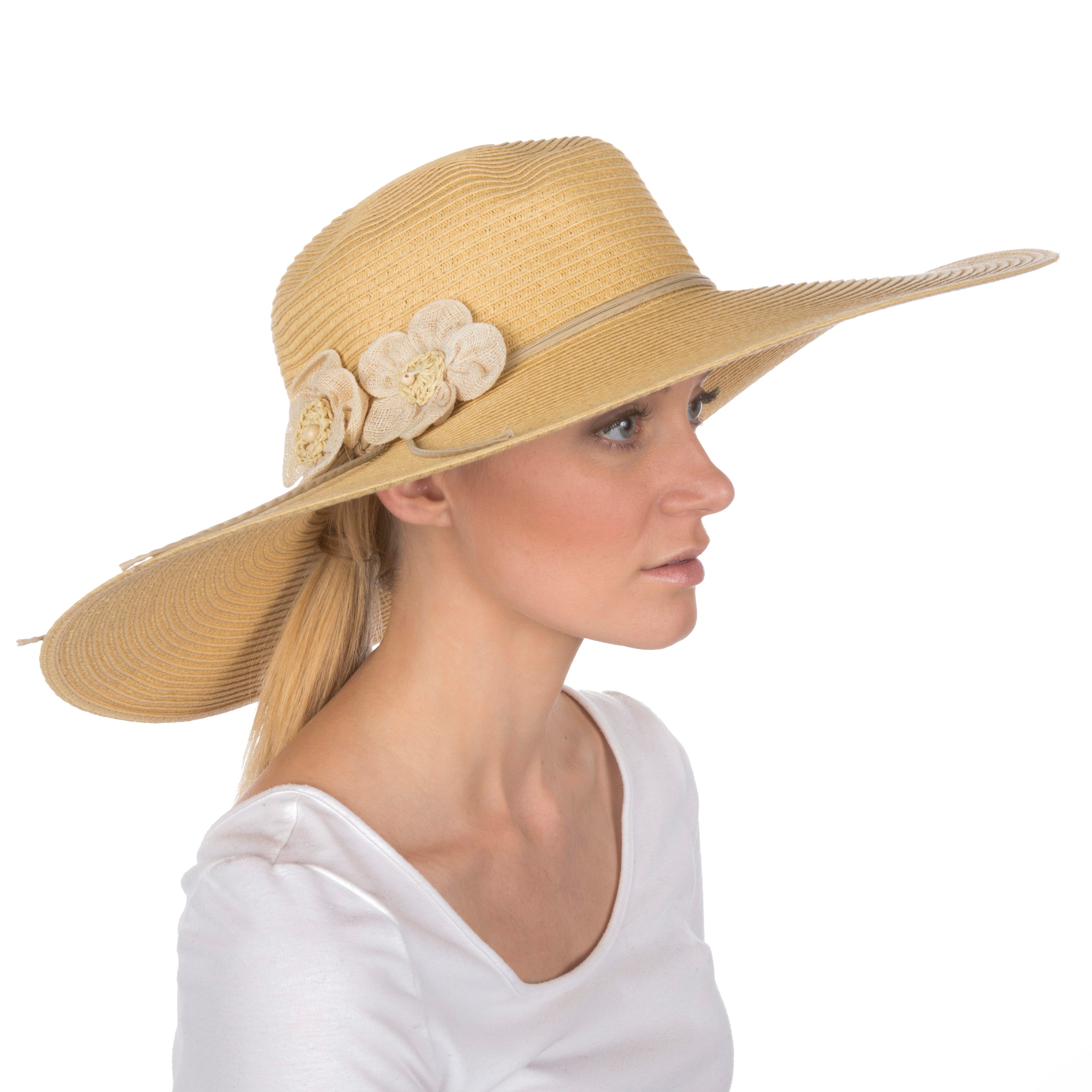Woman wearing a beige straw hat with floral embellishments on a white background