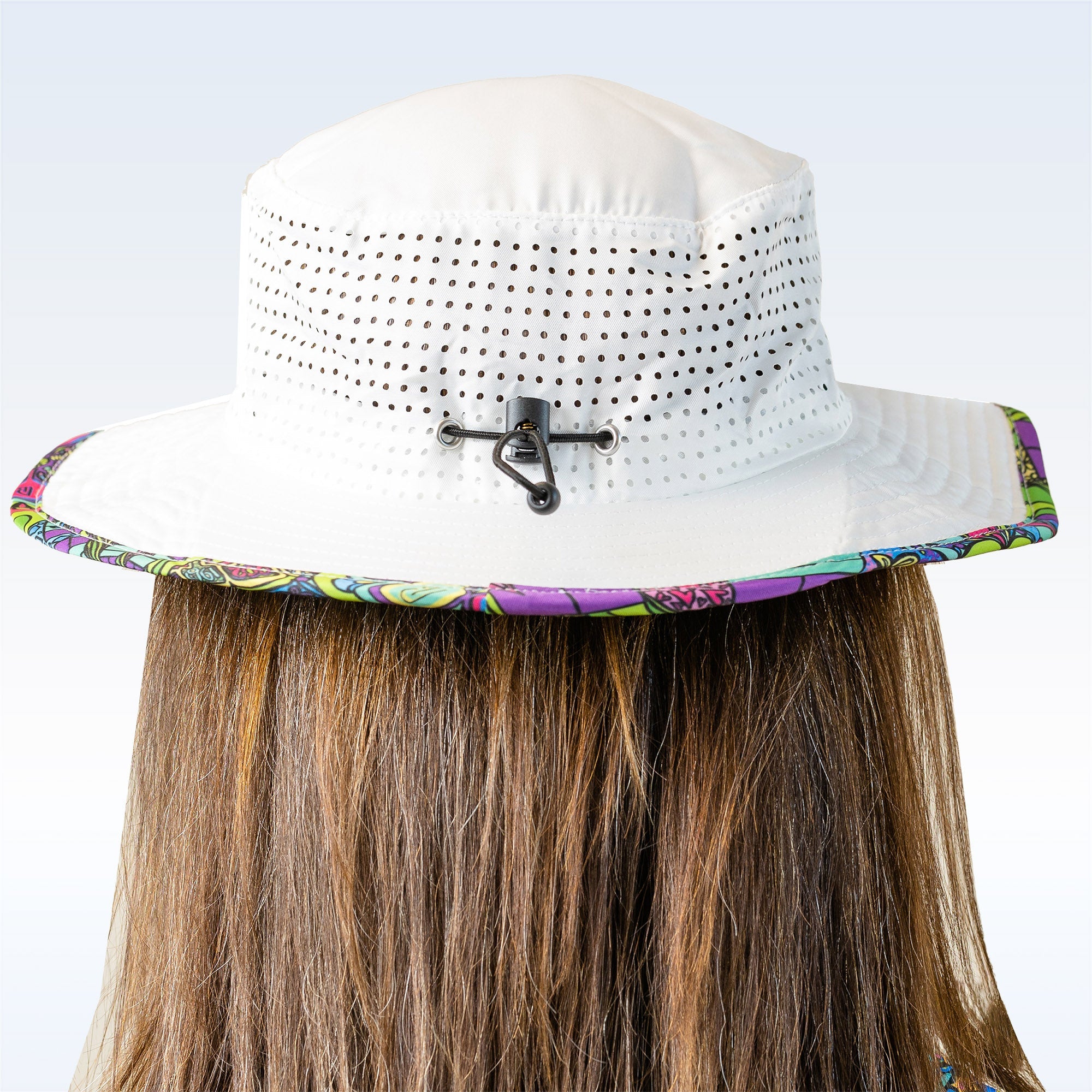 White bucket hat with colorful band worn by a person on a light blue background