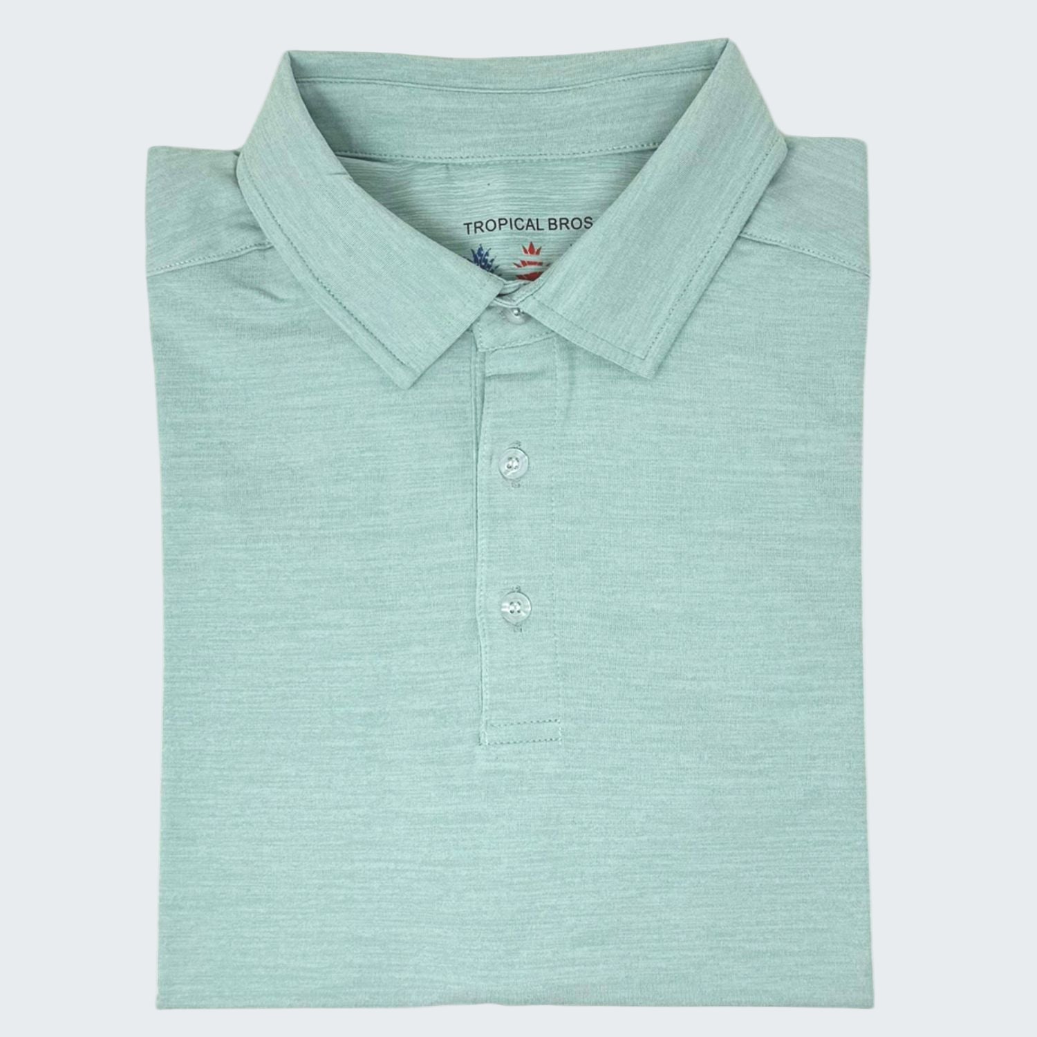 Folded light blue polo shirt with 'Tropical Bros' branding on a white background