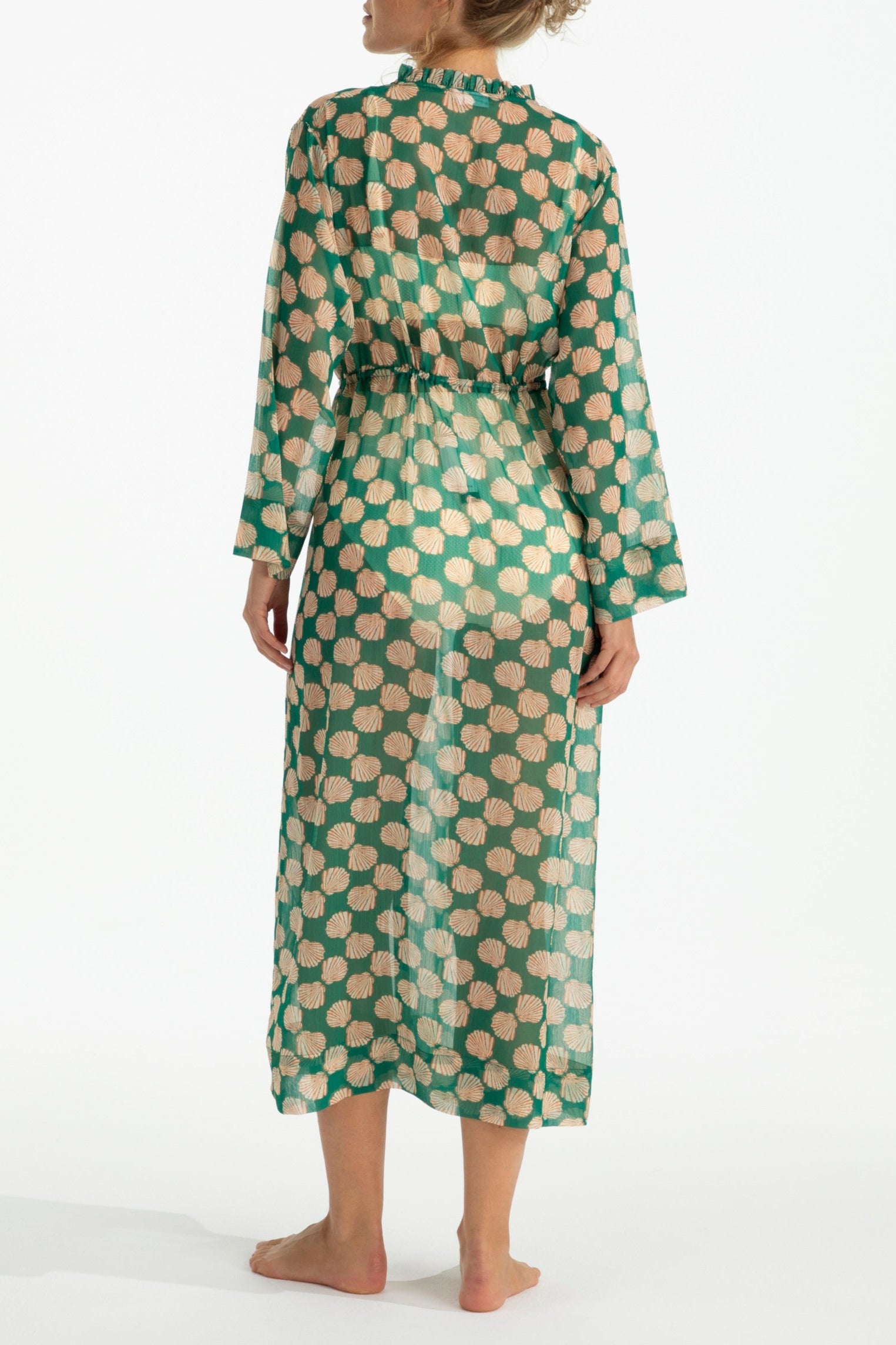 Woman wearing a green and beige patterned dress on a white background