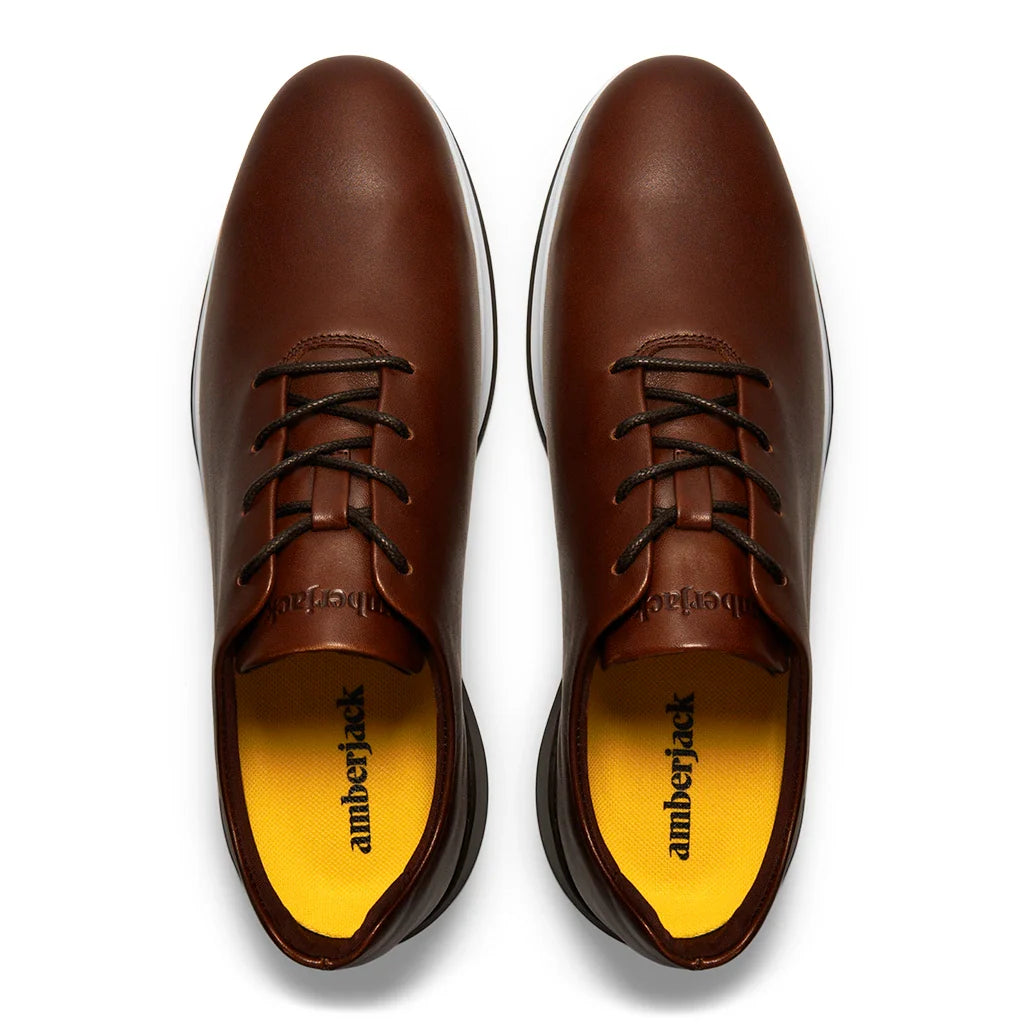 Brown leather shoes with black laces and yellow lining on a white background