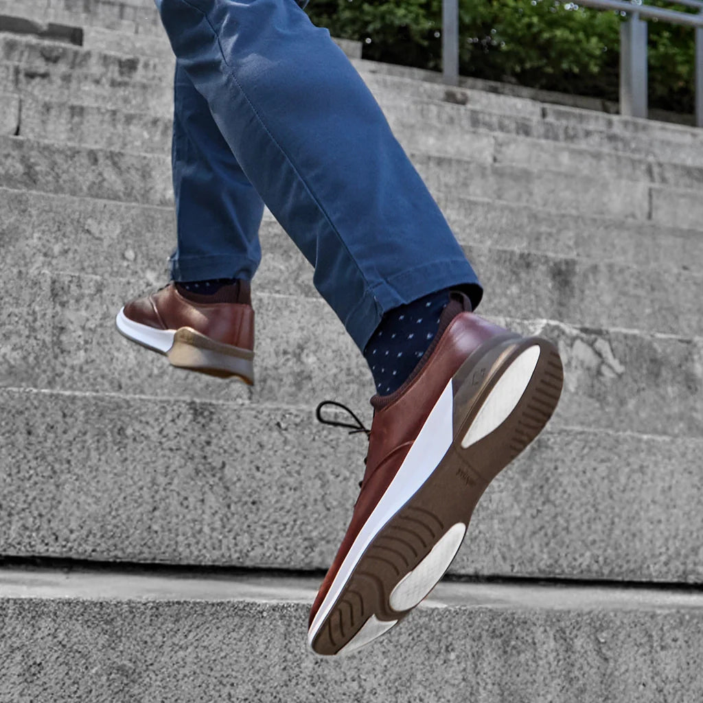 Person wearing brown shoes with white soles climbing a set of concrete stairs.