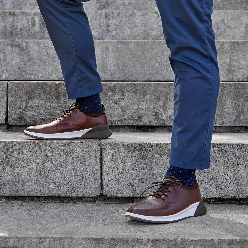 Person wearing brown shoes and blue pants standing on stone steps.