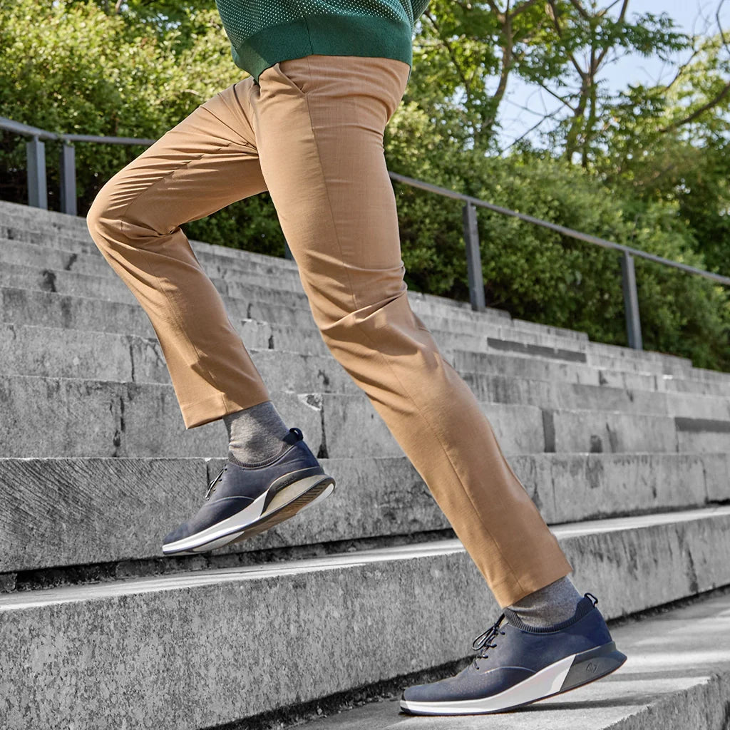 Person wearing beige pants and navy shoes climbing stairs outdoors