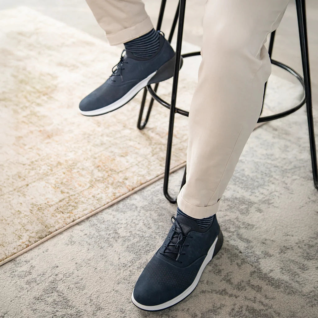 Person wearing navy blue shoes with white soles on a light-colored floor.