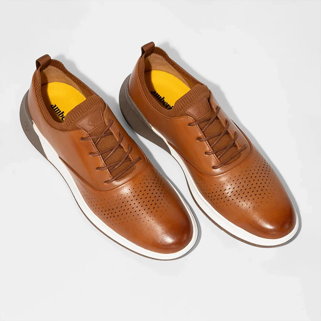 Pair of brown leather shoes with white soles on a light gray background
