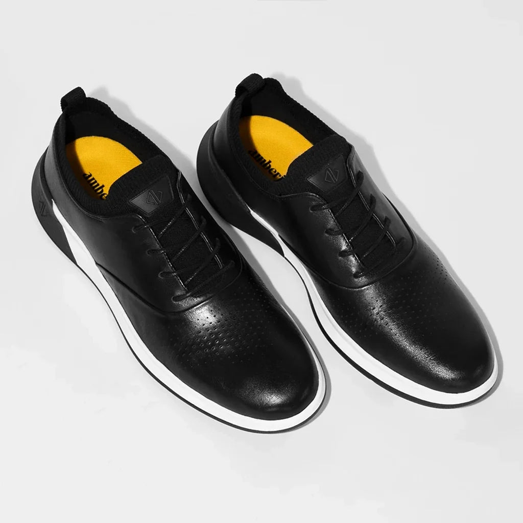 Black leather shoes with yellow sole on a light gray background
