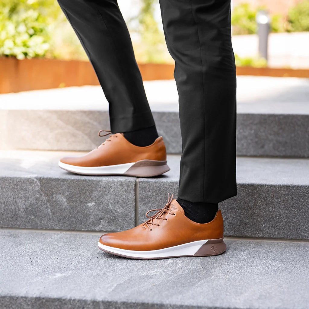 Person wearing brown shoes and black pants on a stone step.