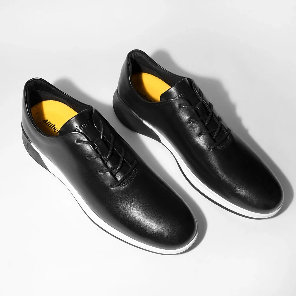 Black leather shoes with yellow lining on a white background