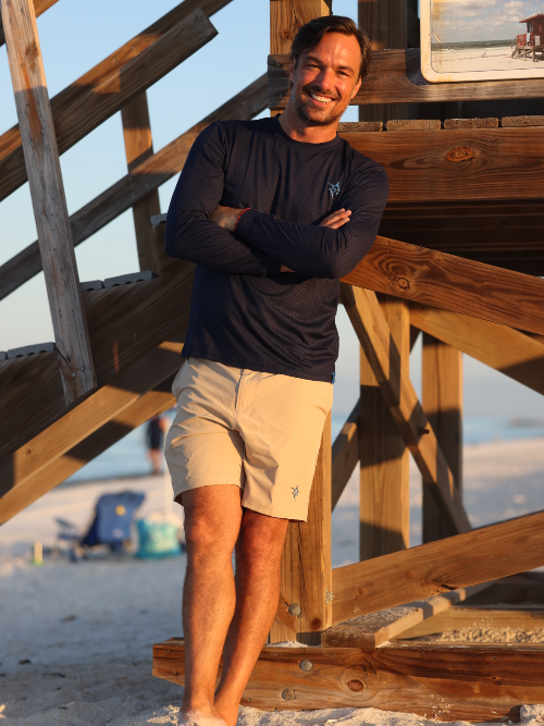 Man standing on a wooden staircase at the beach with arms crossed