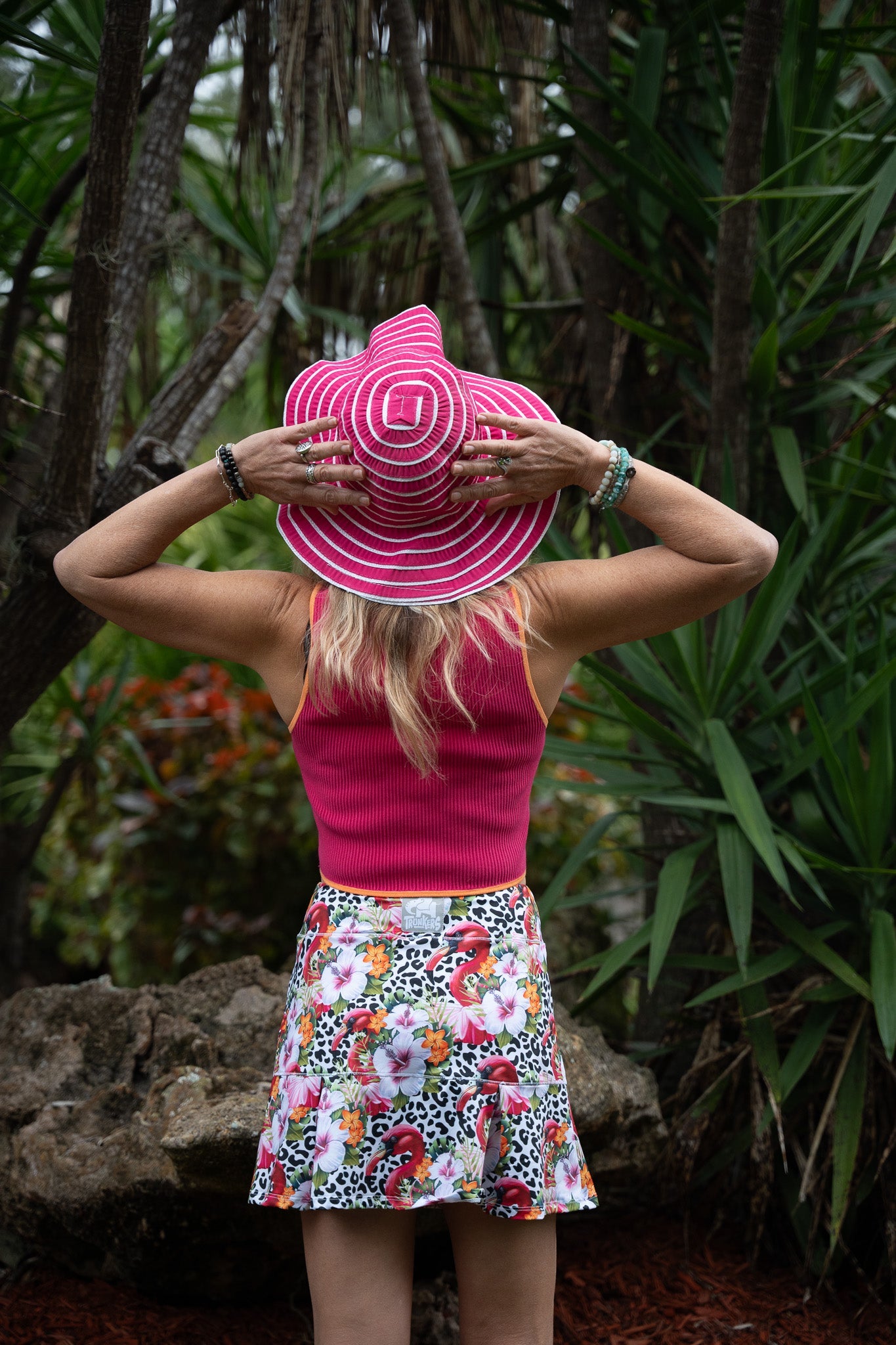 Person wearing a pink sun hat with a patterned skirt in a forest setting