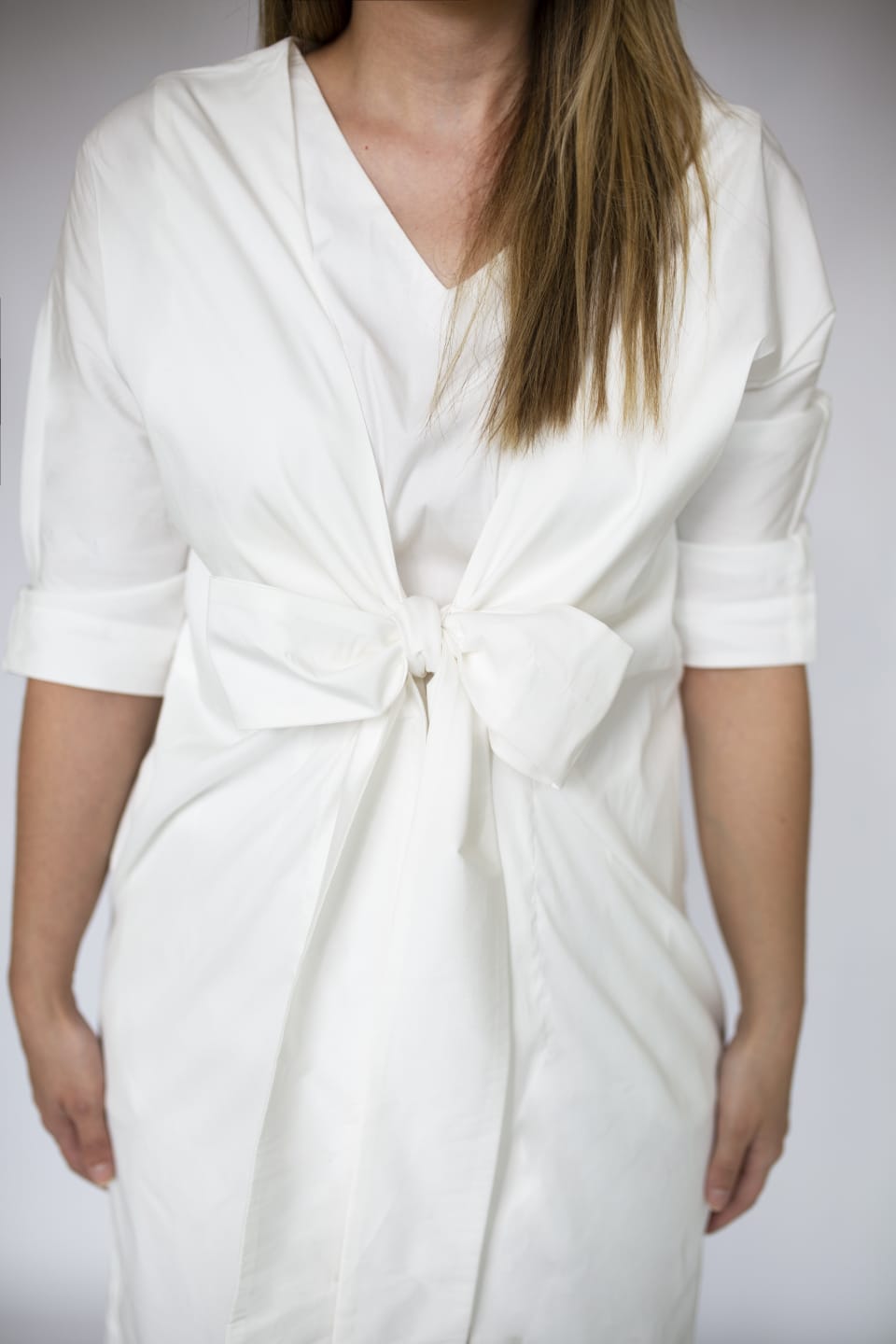 White dress with a knot detail on a plain background