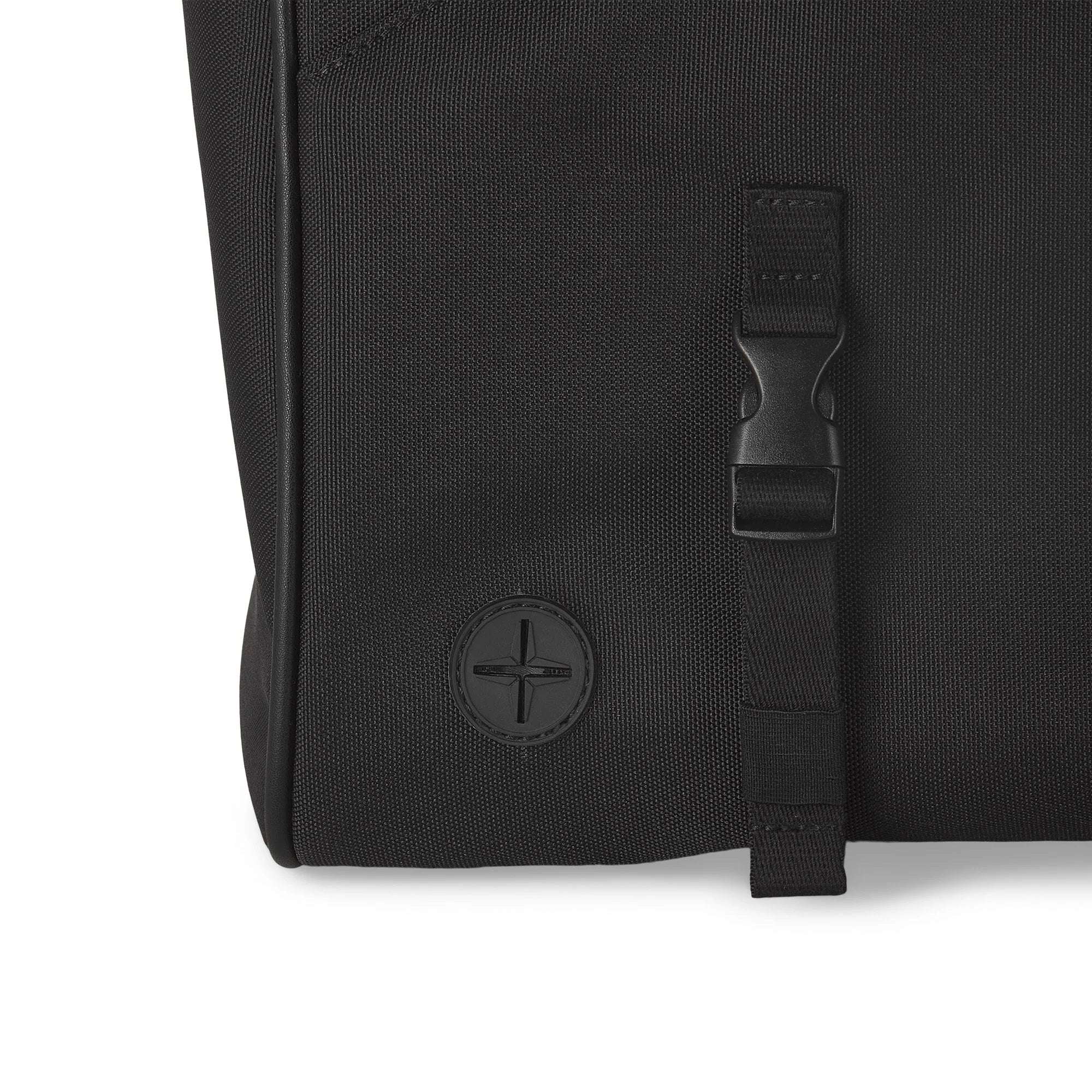 Close-up of a black backpack with a buckle and brand logo on a white background