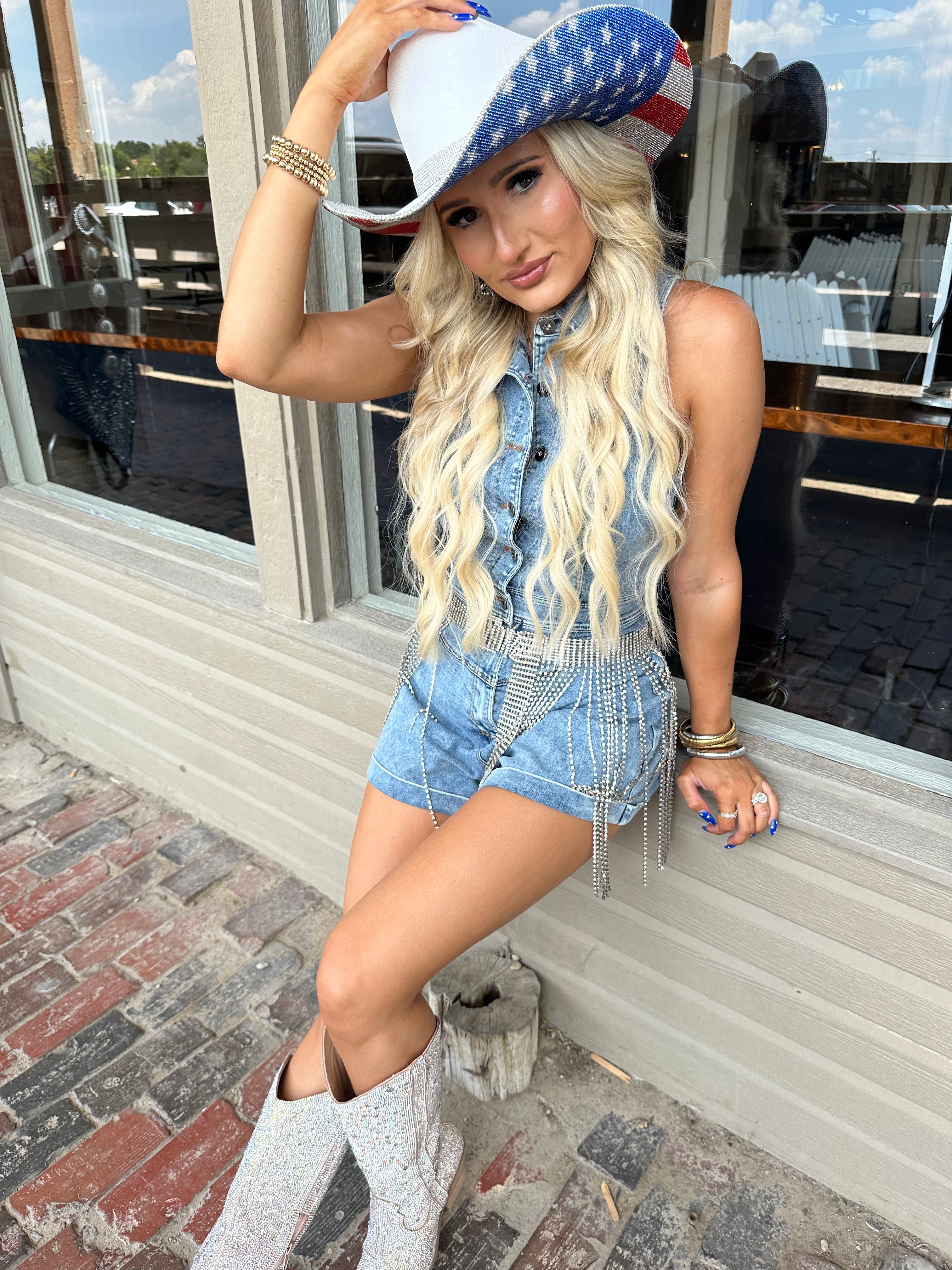 Woman wearing a denim outfit and American flag hat outdoors.