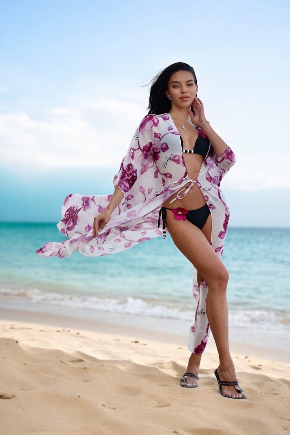 Woman in a floral cover-up and black bikini on a beach