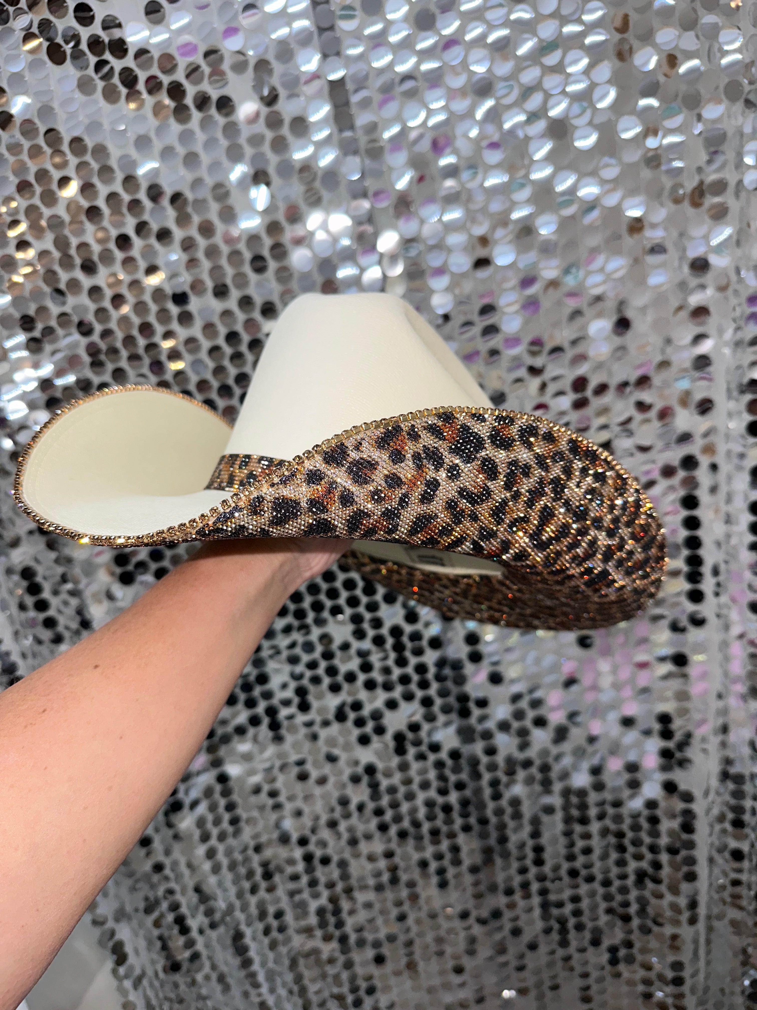 Shoe with leopard print trim held against a sequin background