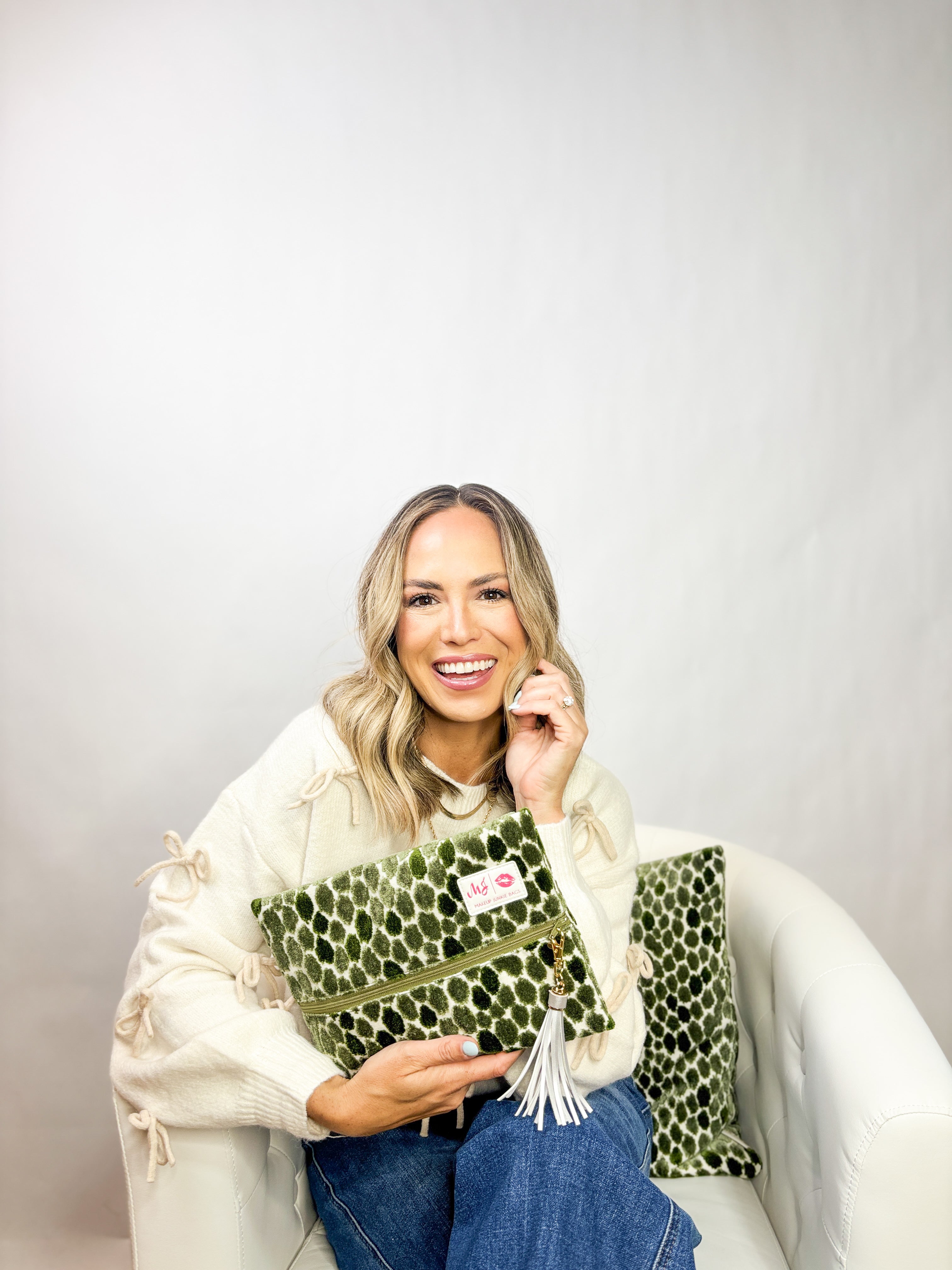 Woman holding a green clutch with leopard print pattern against a plain background