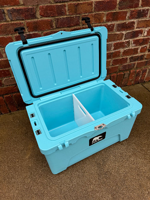 Blue cooler box with a black lid against a brick wall.