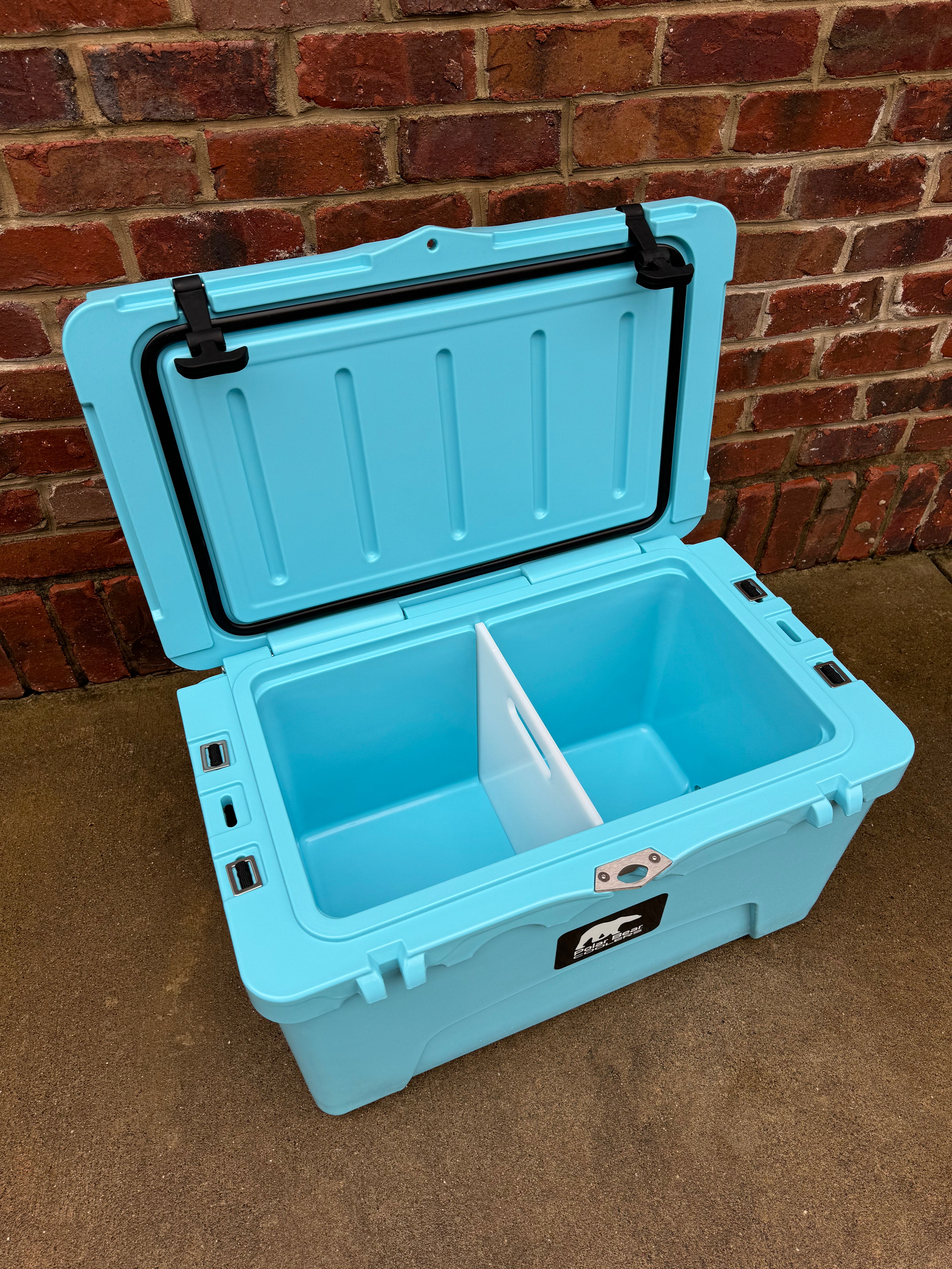 Blue cooler box with open lid against a brick wall background