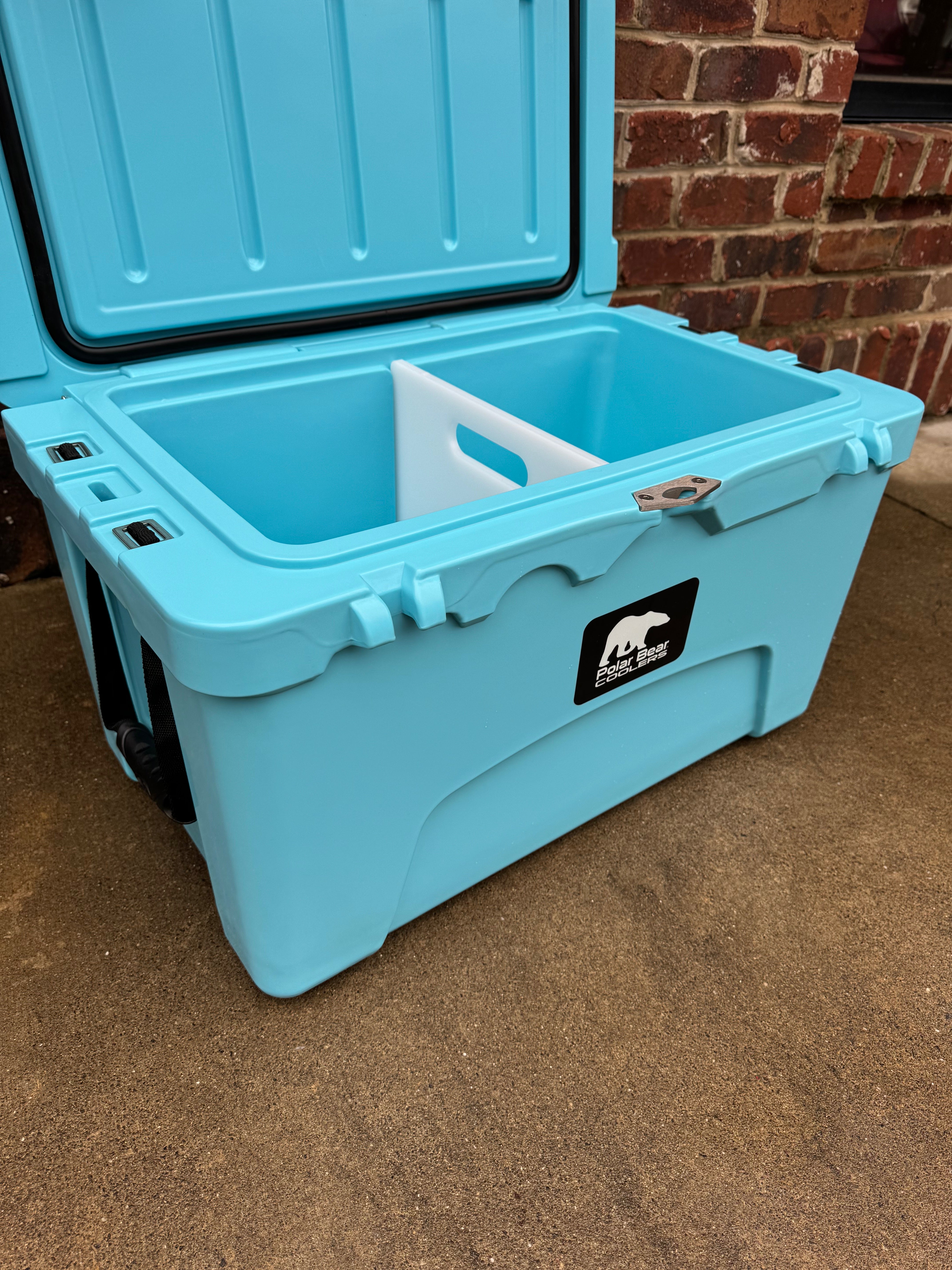 Blue cooler box with a logo on a brown surface and brick wall background