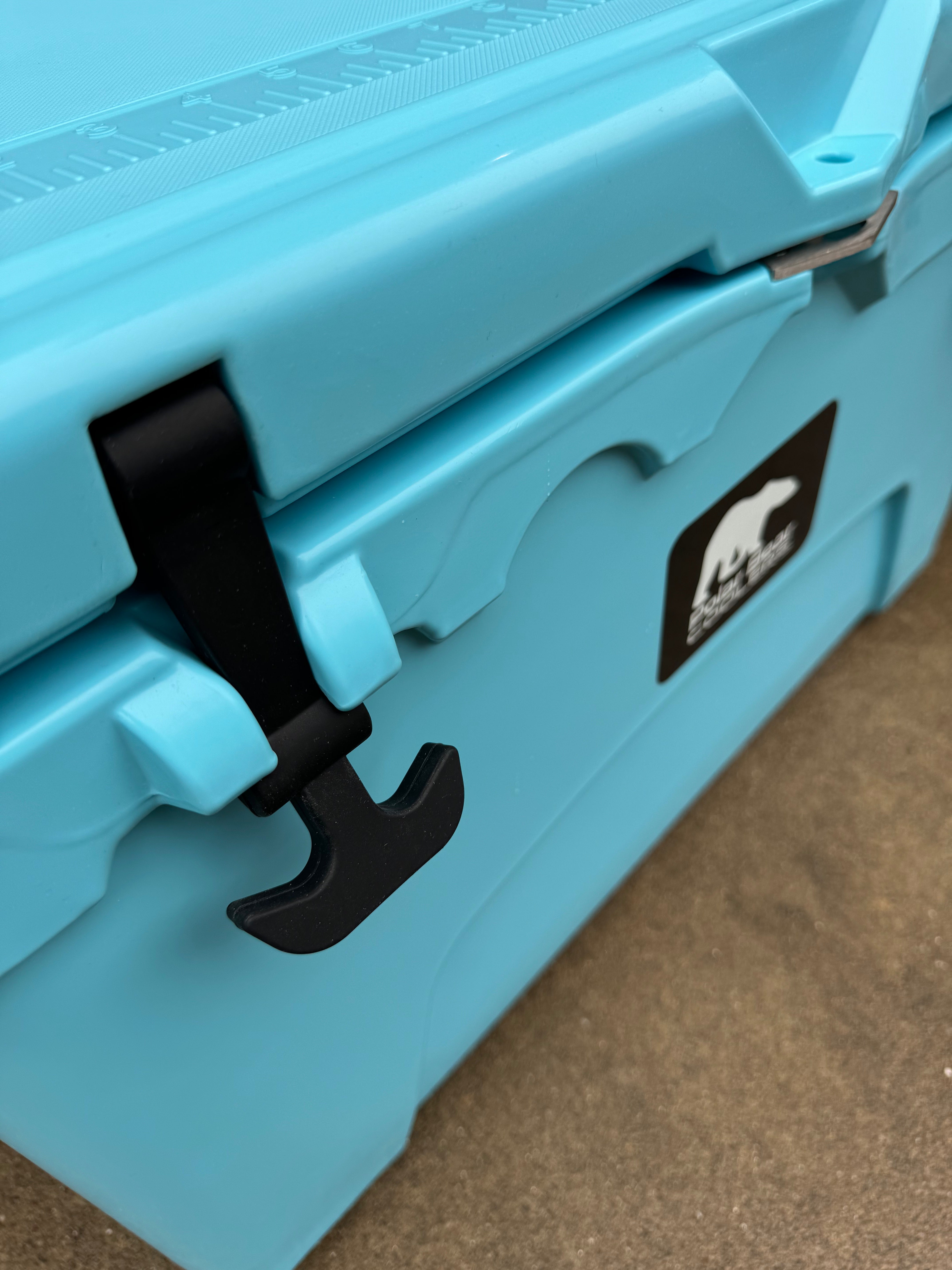 Close-up of a blue cooler with a black handle and logo on a brown surface